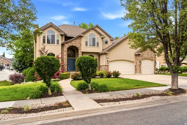 Stucco and stone facade home featuring an arched entry, a two-car garage, and a separate single-car garage