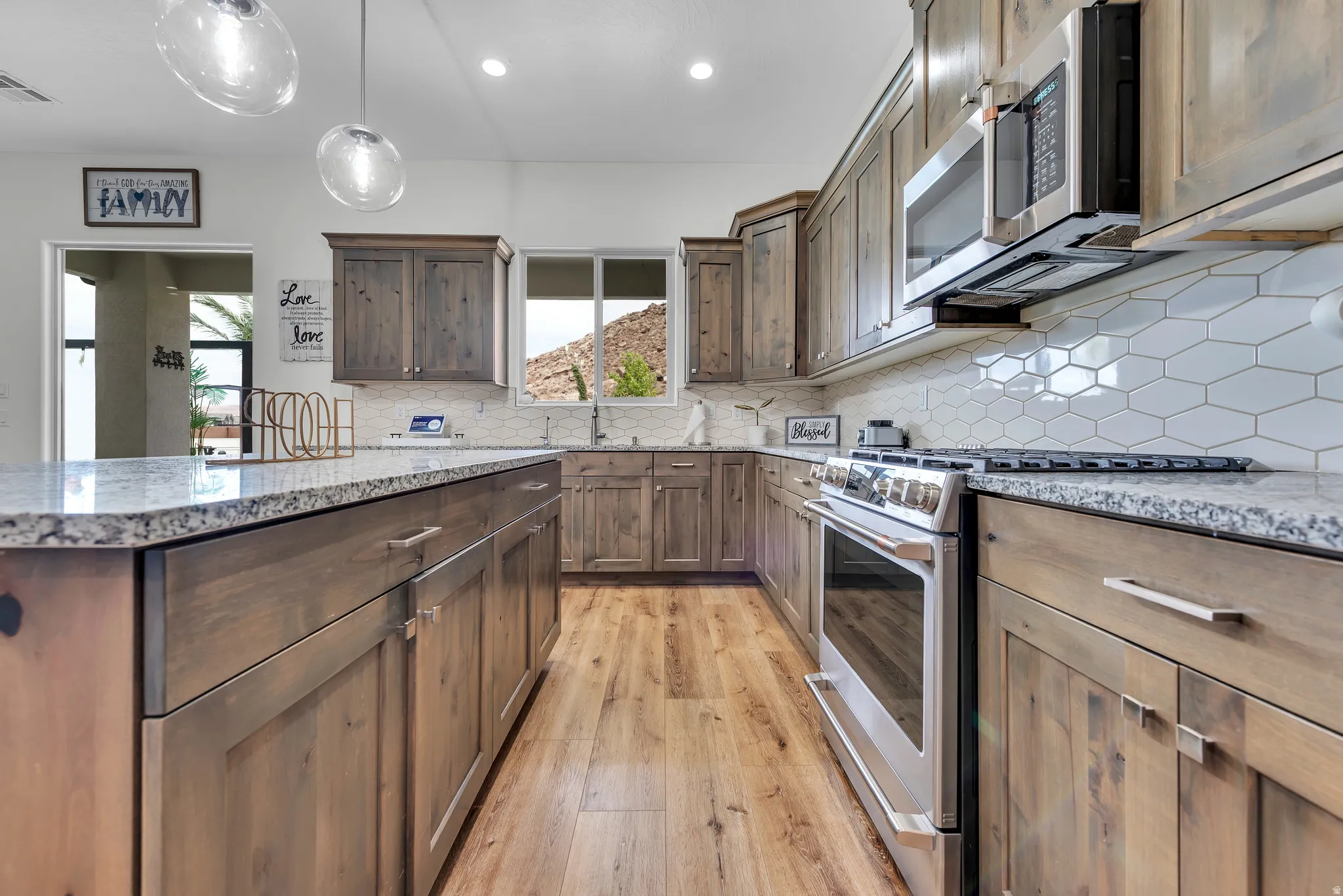 Kitchen featuring wood-finish cabinetry, granite-style countertops, stainless steel appliances, a white geometric tile backsplash, and wood-finish flooring