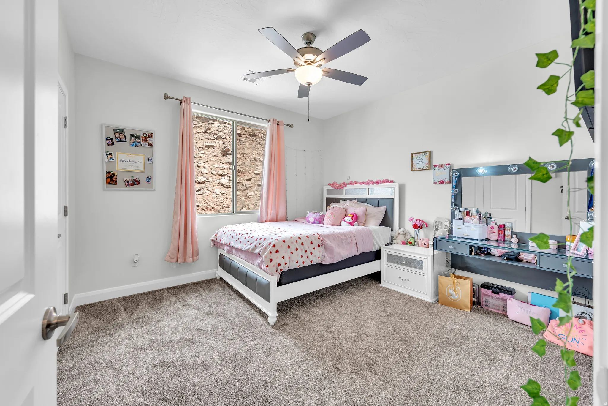 Carpeted room with a ceiling fan, a window with natural light, and ample wall space