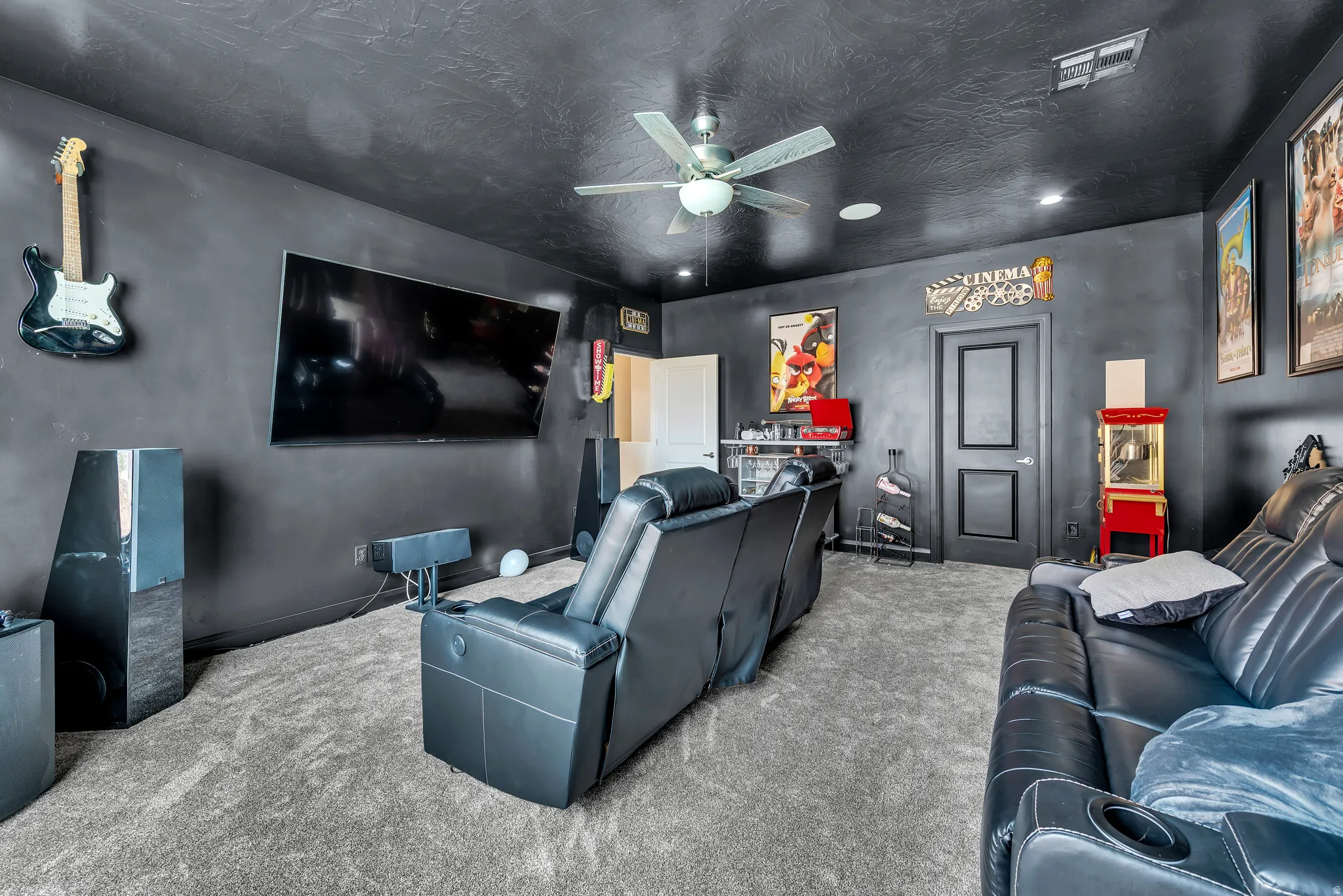 Dedicated media room featuring dark walls, textured ceiling, and gray carpeting