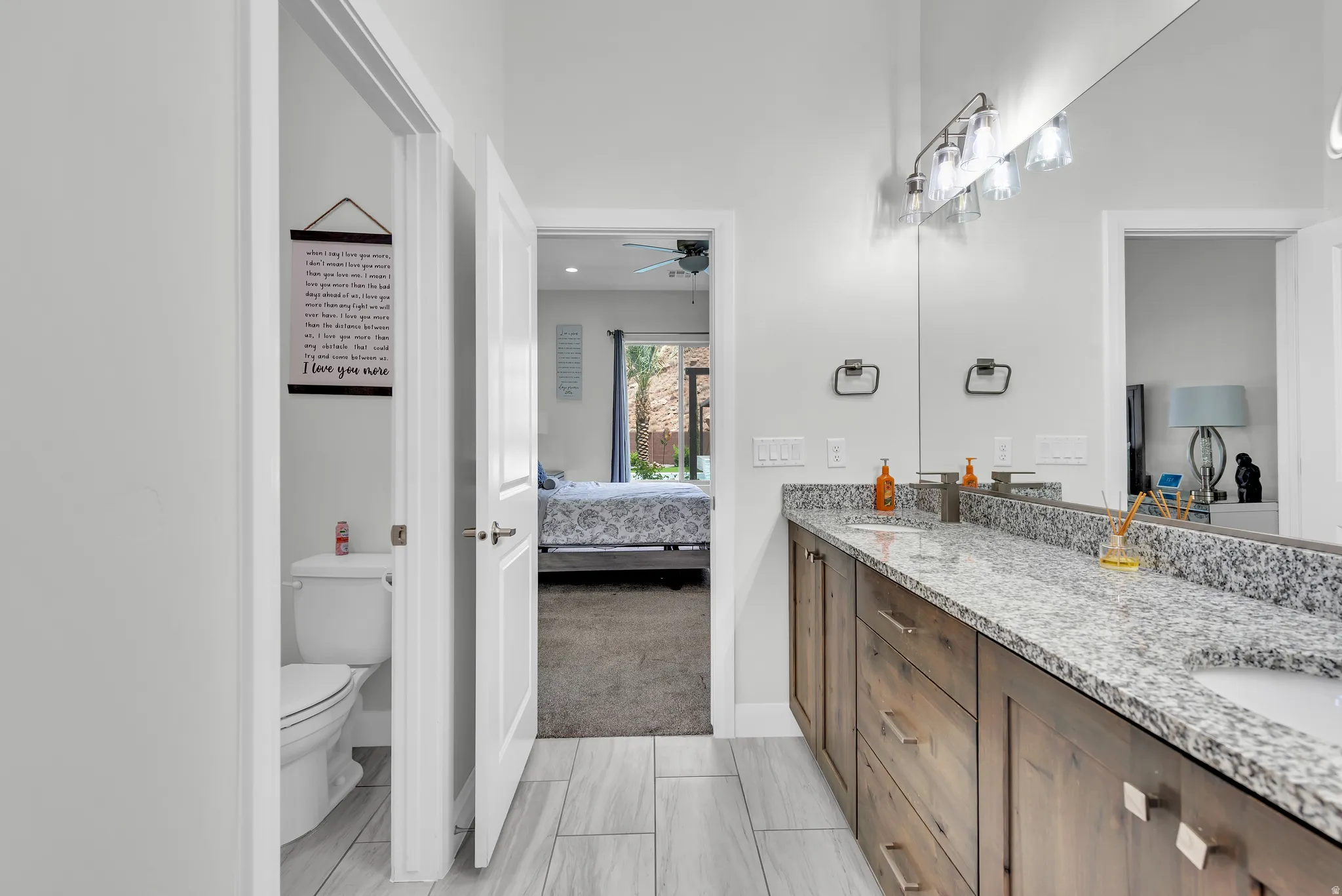 Bathroom vanity featuring a dual sink, granite countertop, and wood-finish cabinetry