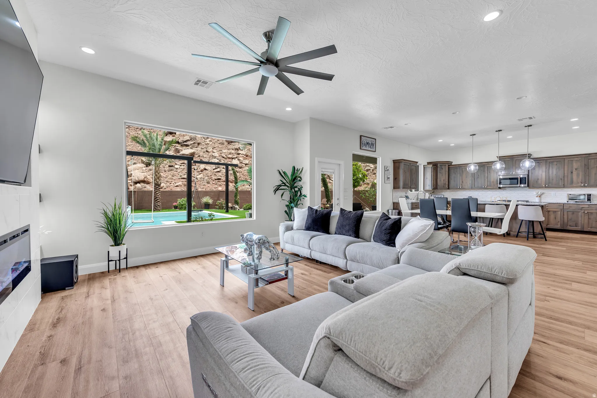 Spacious open-concept living area featuring wood-finish flooring, recessed lighting, and a modern ceiling fan