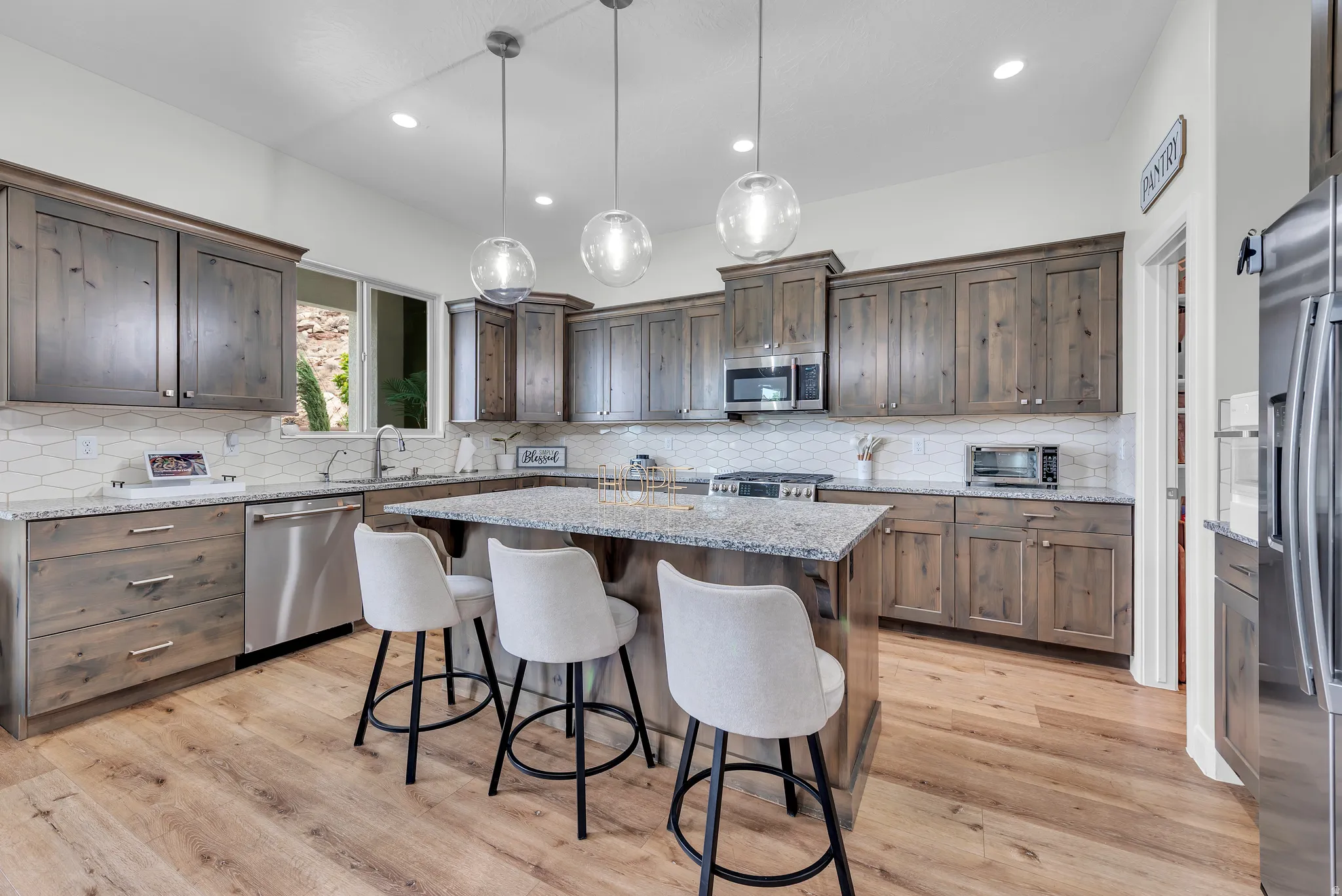 Spacious kitchen featuring wood-finish flooring and extensive cabinetry with polished hardware