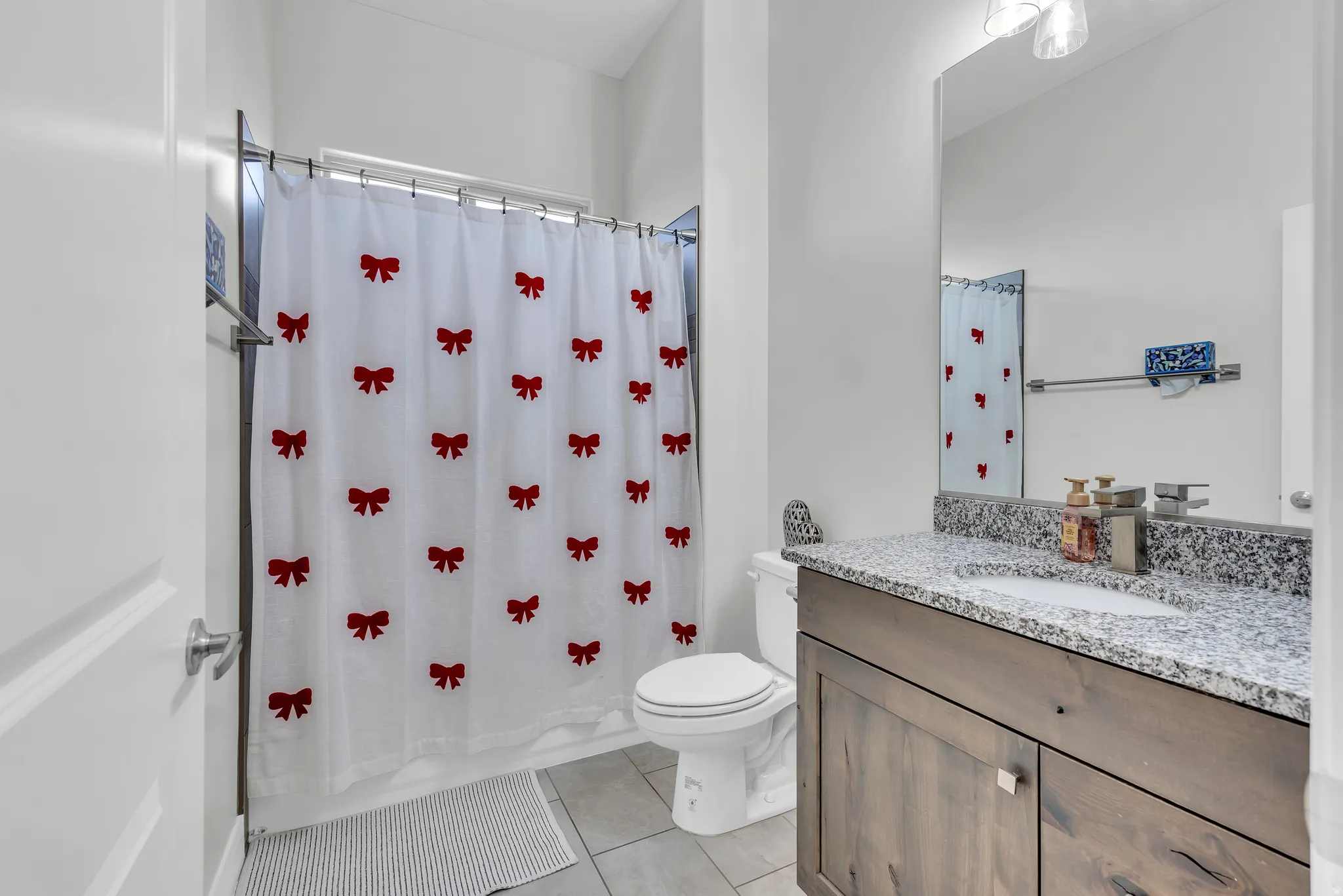 Contemporary bathroom featuring a single-sink vanity with a granite-look countertop and wood-finish cabinetry