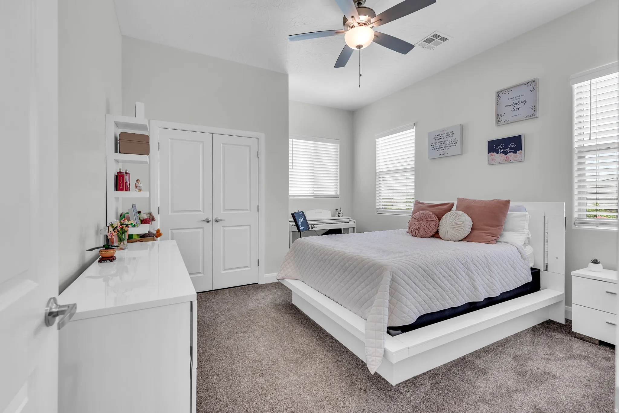 Vaulted ceiling with a ceiling fan, dual windows with blinds, built-in shelving, and white bi-fold closet doors