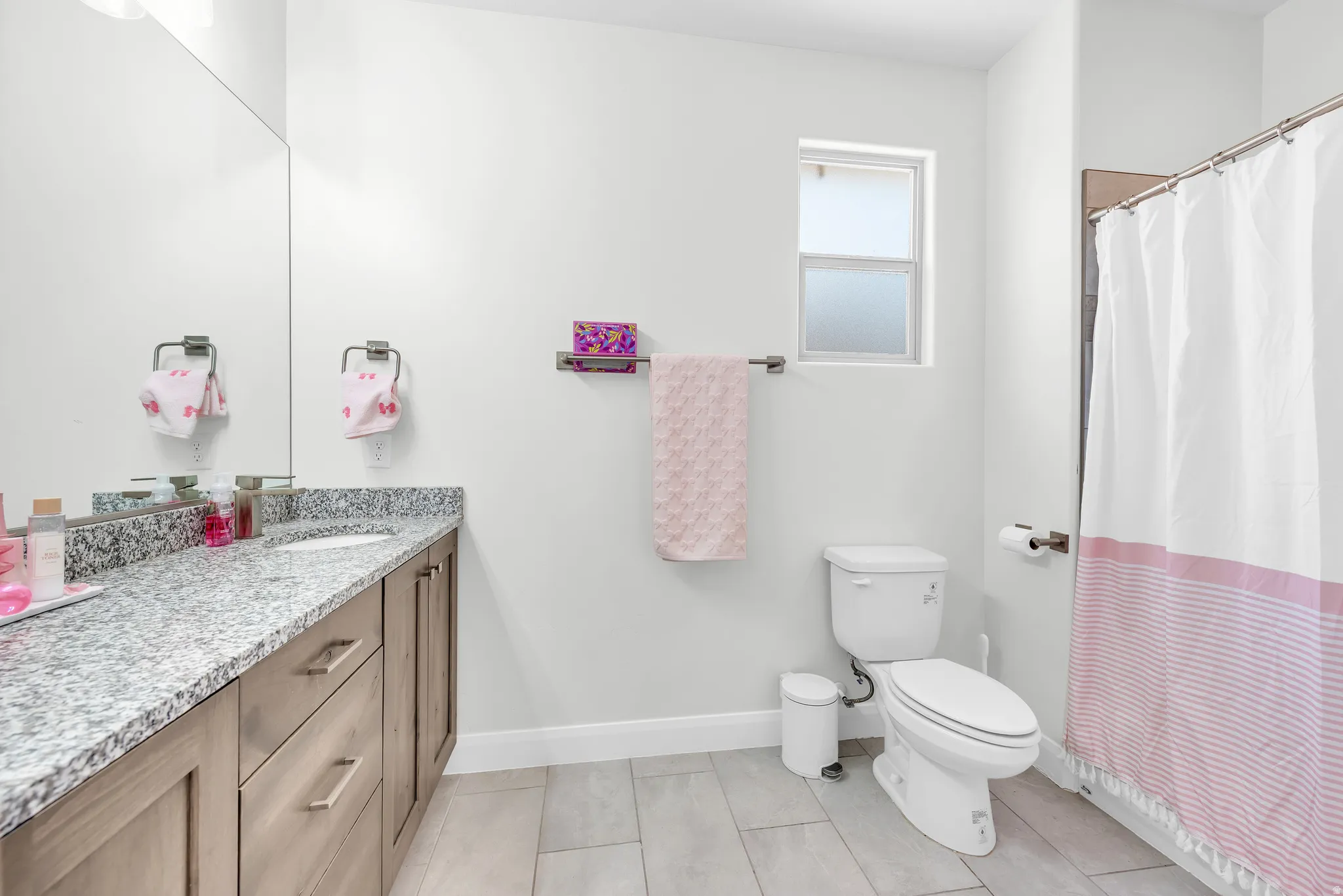 Bathroom featuring a single vanity with stone countertop, undermount sink, and wood-finish cabinetry