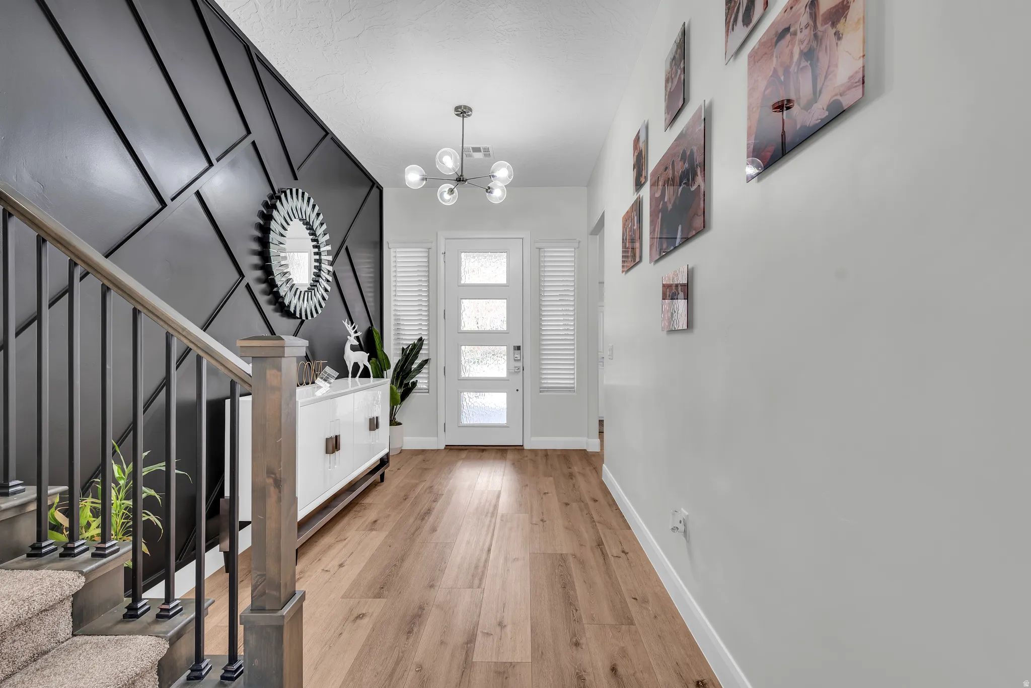 Entryway featuring a contemporary geometric accent wall and wood-finish flooring