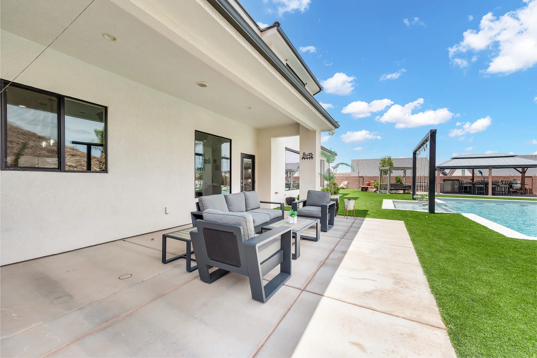 Expansive outdoor living area featuring a covered patio, a swimming pool, artificial turf, and a built-in gazebo with a bar area
