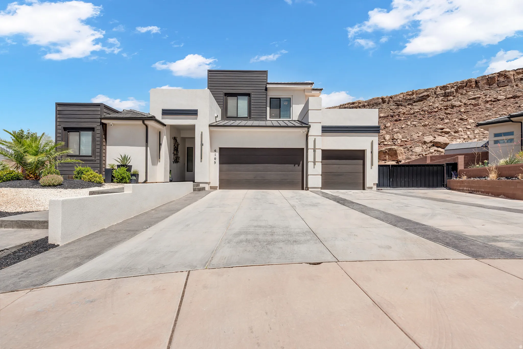 Modern architectural residence with a white stucco facade and dark horizontal siding accents