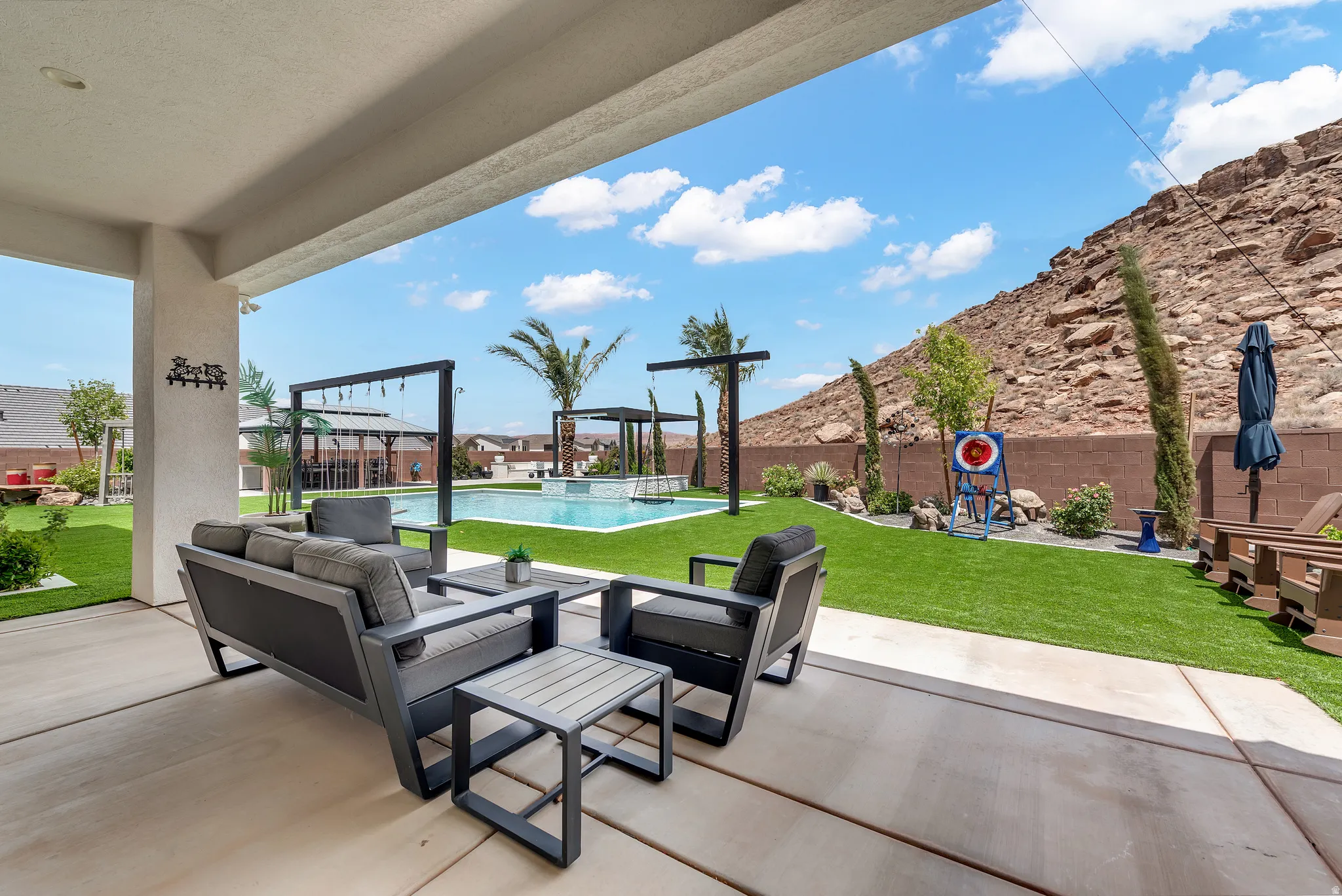 Expansive covered patio overlooking a custom swimming pool with integrated spa and waterfall features
