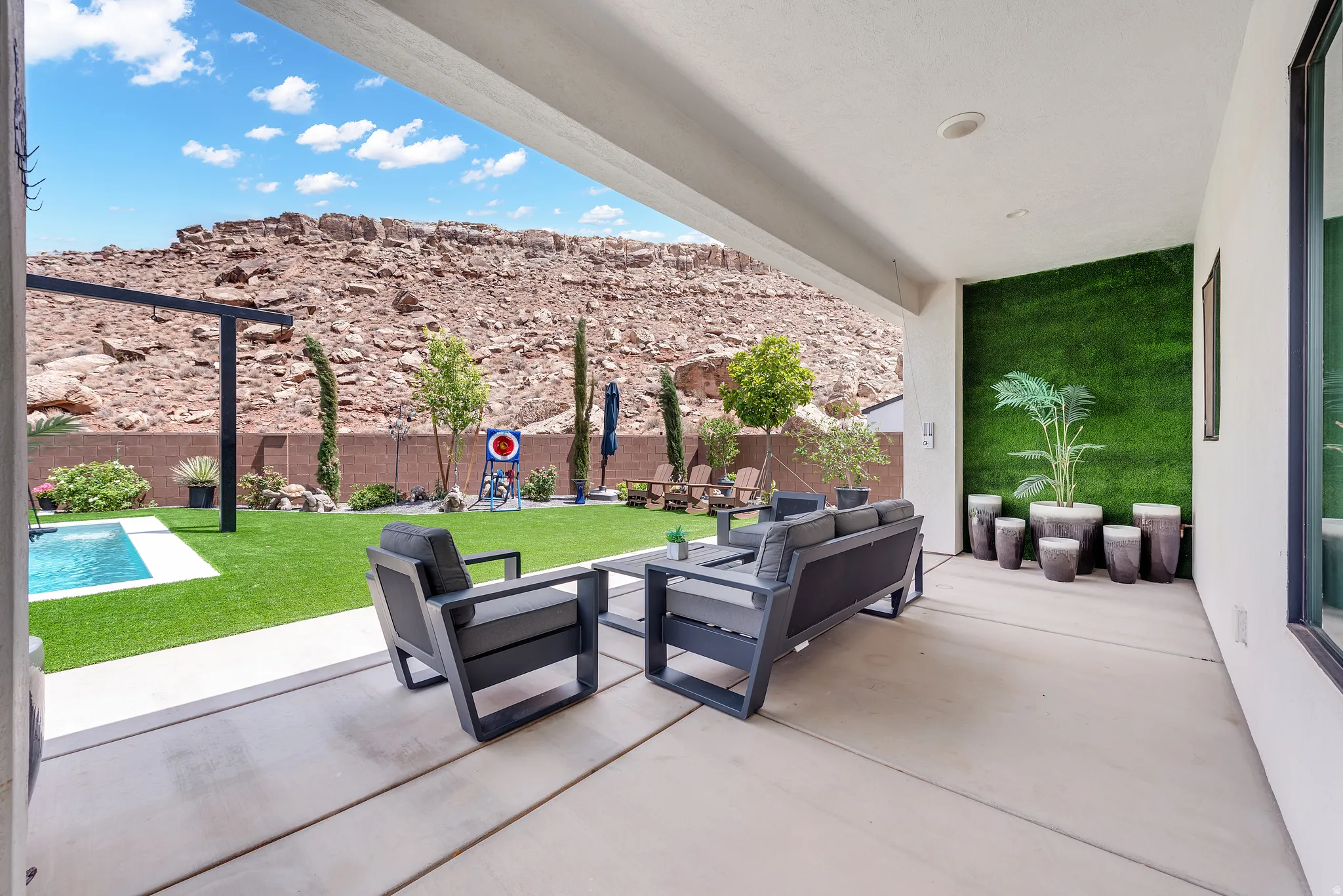 Covered patio featuring an artificial grass wall and concrete flooring