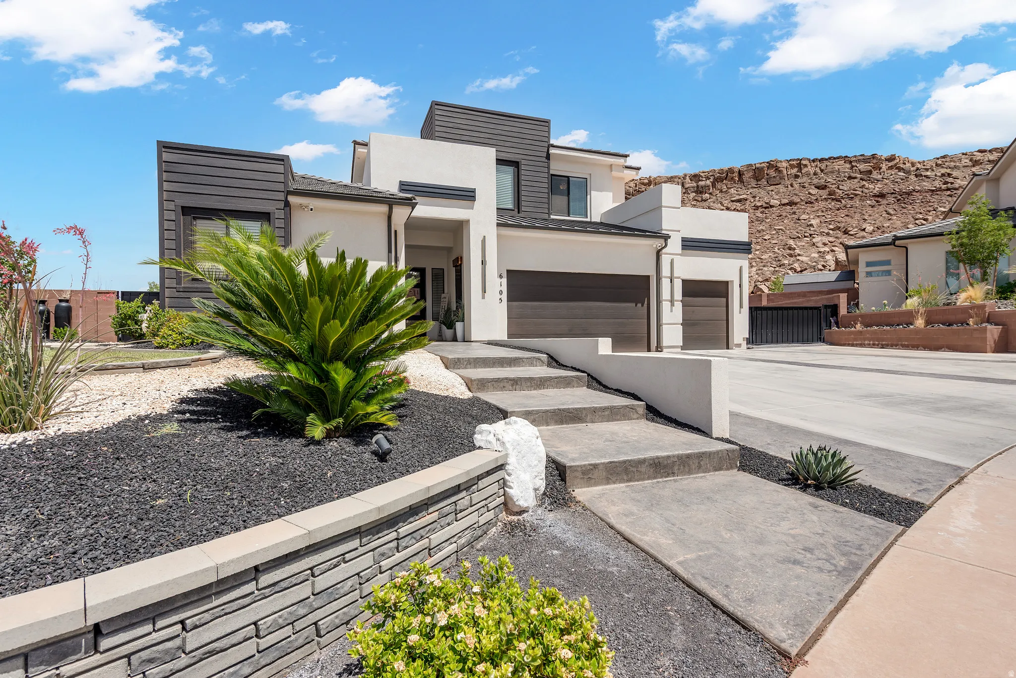 Modern architectural exterior featuring white stucco, dark paneling, and a multi-level design