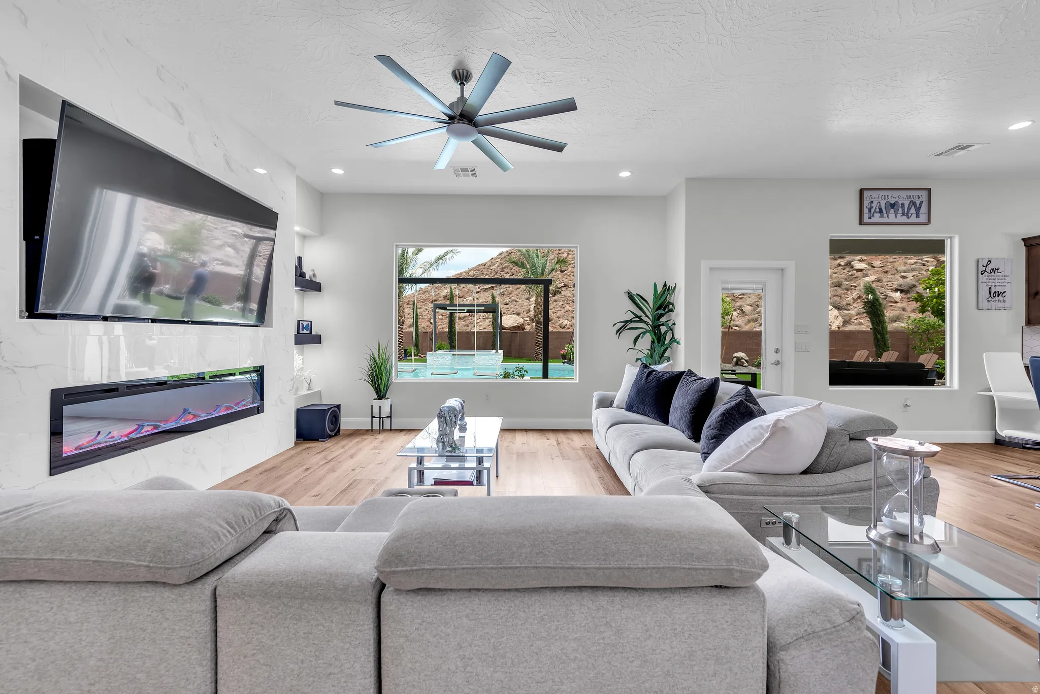 Living area featuring a modern linear electric fireplace, wood-finish flooring, recessed lighting, and a contemporary ceiling fan