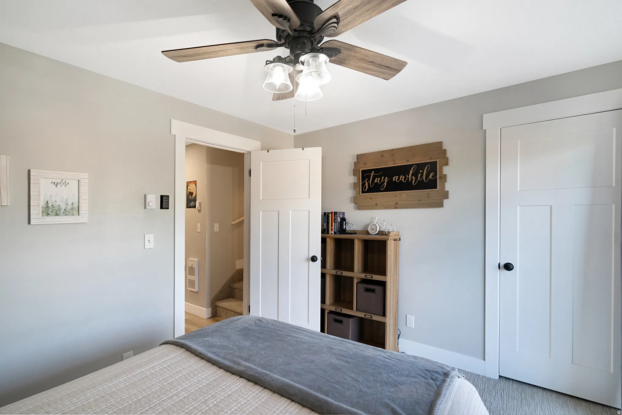 Light grey walls with white trim throughout, featuring a ceiling fan with wood-finish blades and integrated lighting