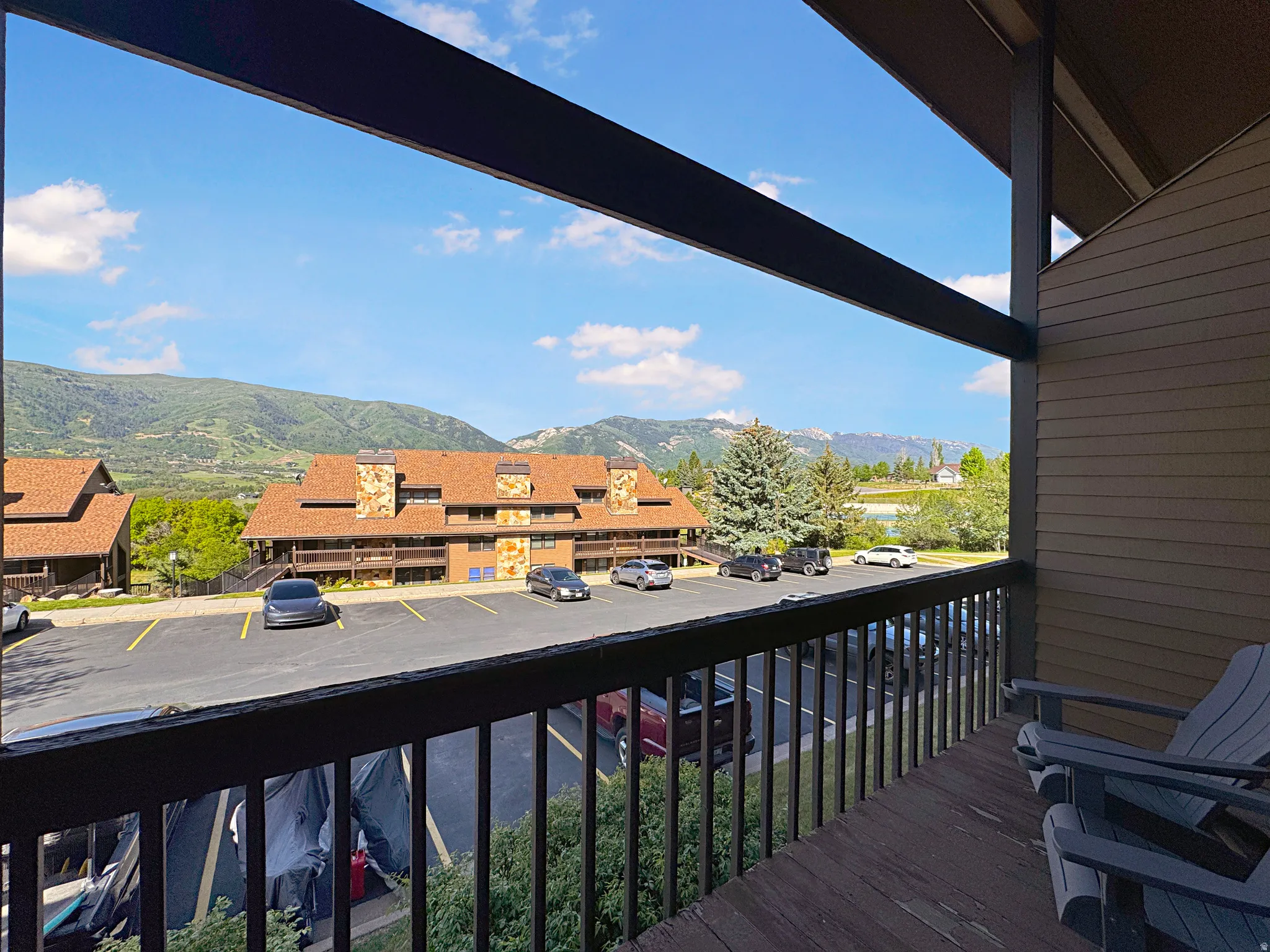 Private balcony featuring wood-finish decking and dark railings