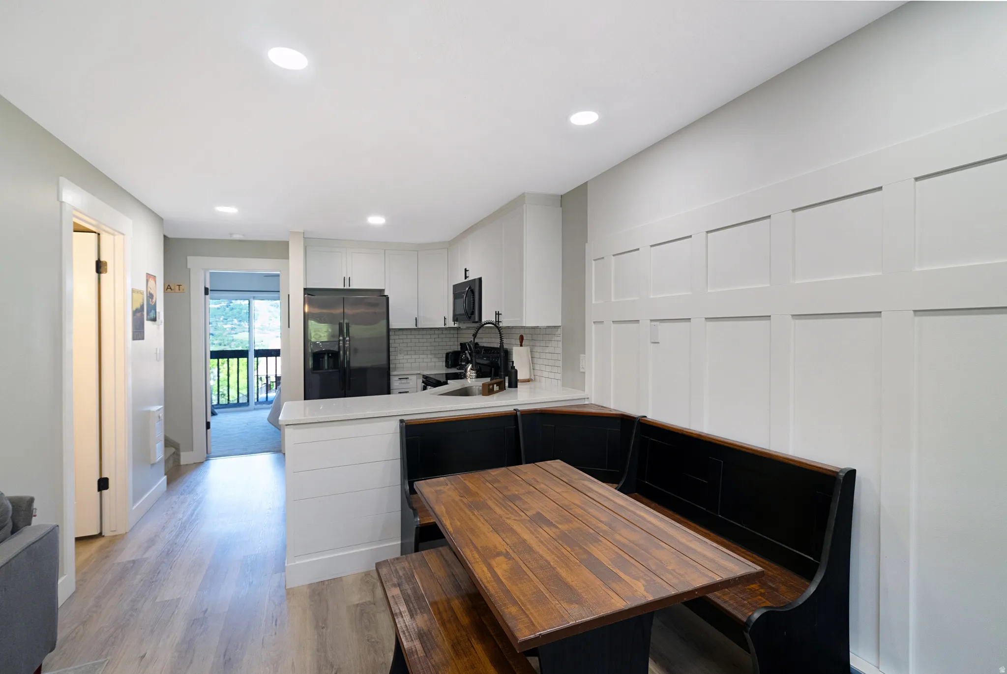 Modern kitchen area featuring light wood-finish flooring, recessed lighting, and a board and batten accent wall