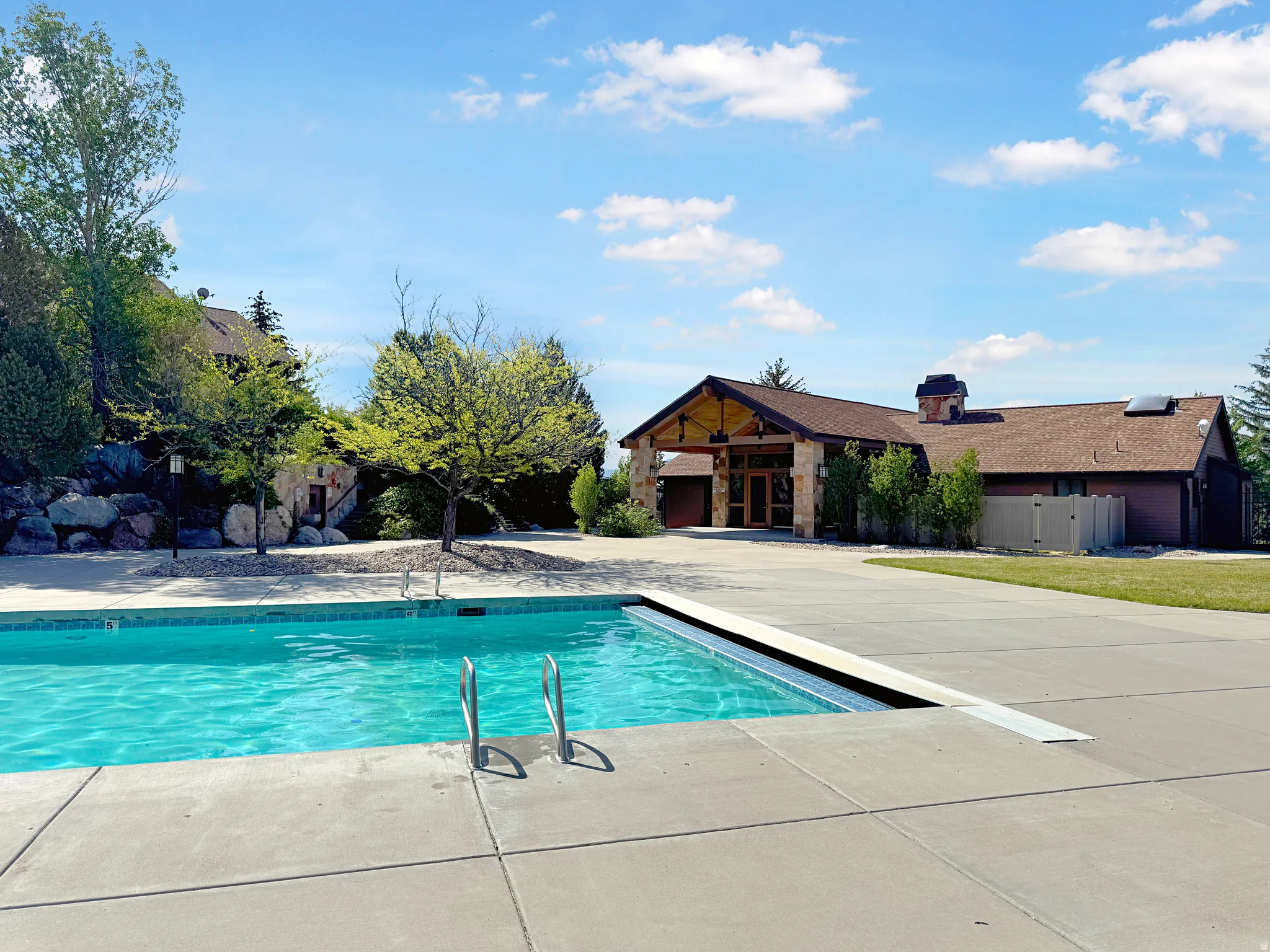 Outdoor swimming pool featuring concrete decking, integrated pool cover, and metal entry rails