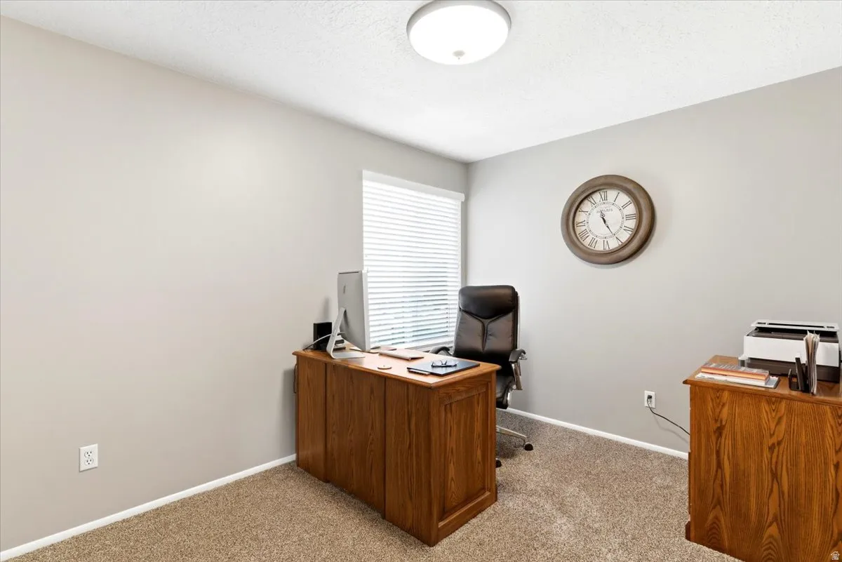 Room featuring neutral wall paint, textured carpeting, and a window with horizontal blinds