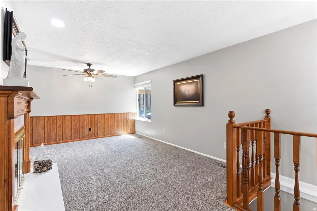 Spacious room featuring light gray walls, wood-finish wainscoting, and a textured gray carpet