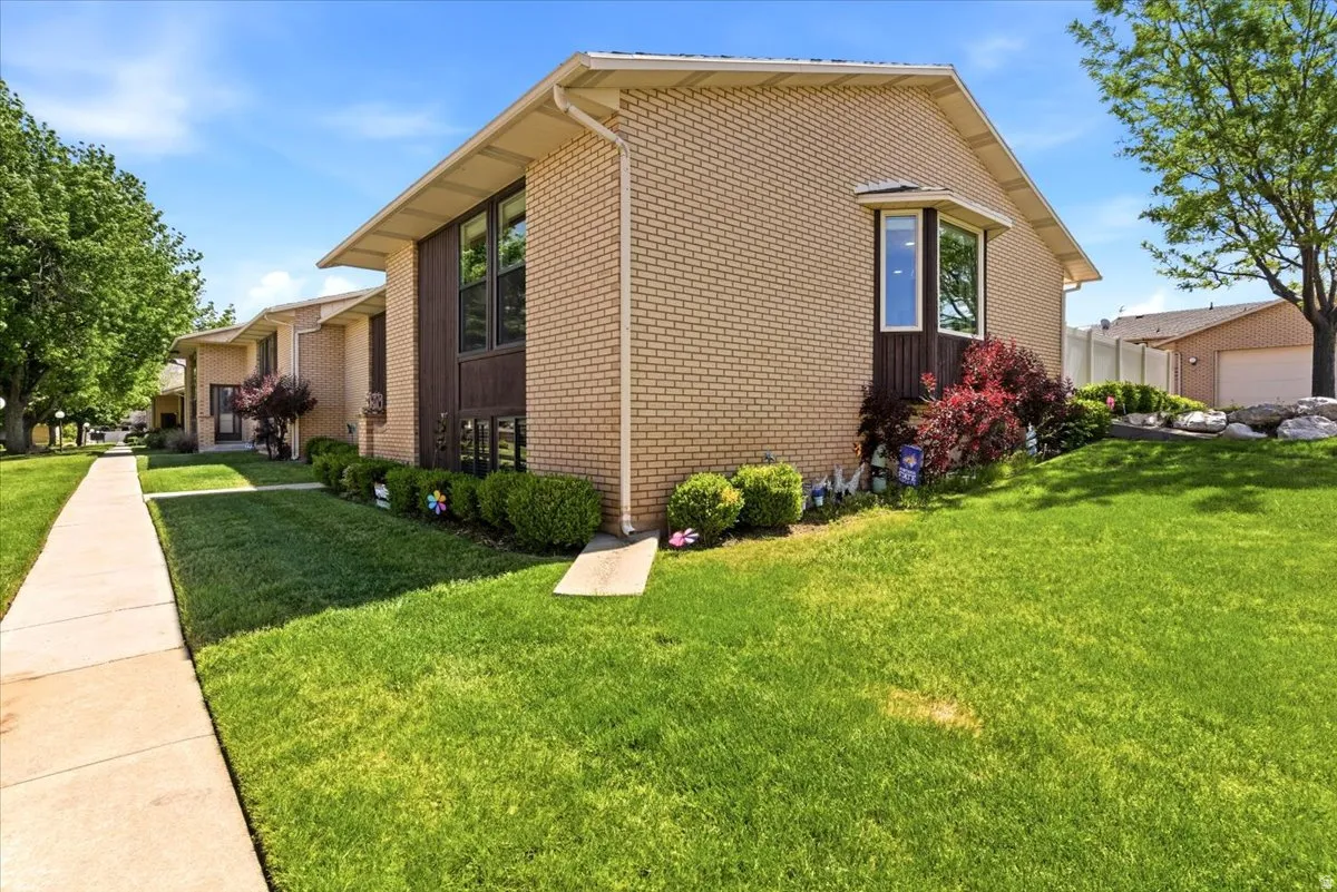 Brick exterior featuring a bay window with white trim, brown paneling, and established landscaping