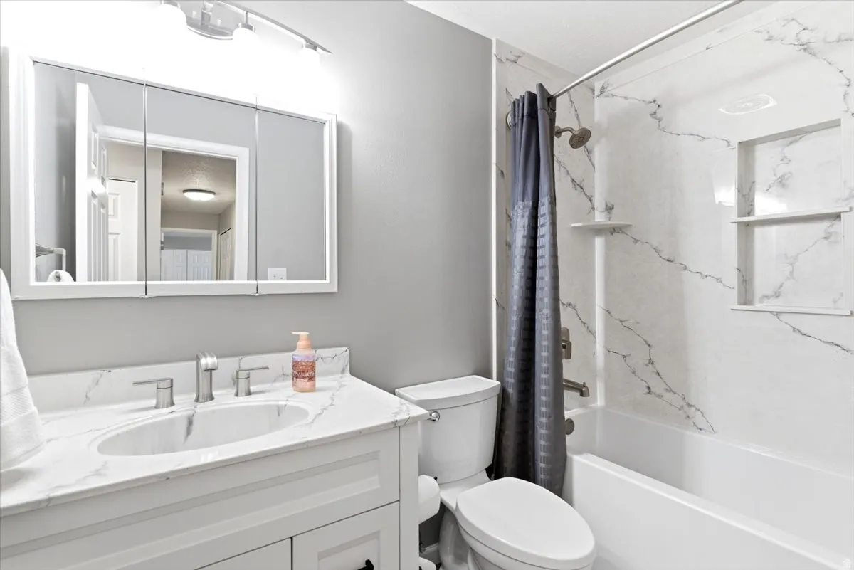Bathroom featuring a white vanity with an integrated sink, brushed nickel faucet, and a large mirrored medicine cabinet