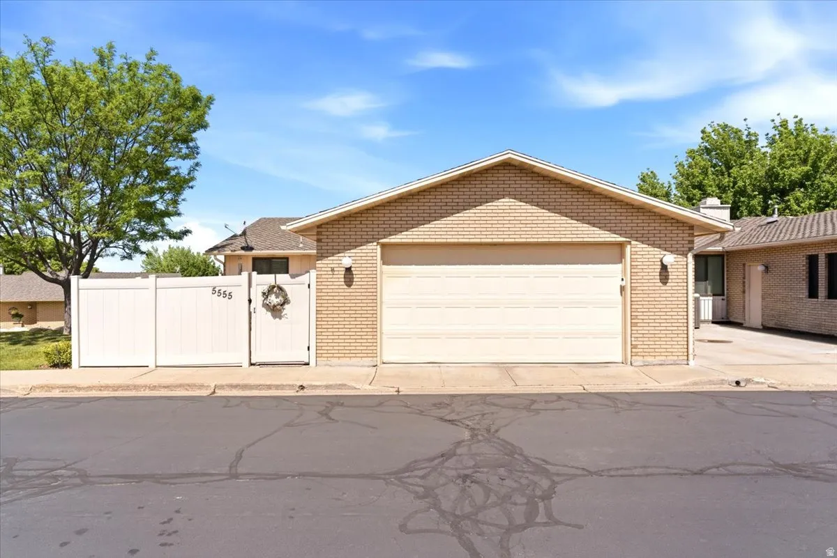 Attached two-car garage with a light brick facade and a white privacy fence