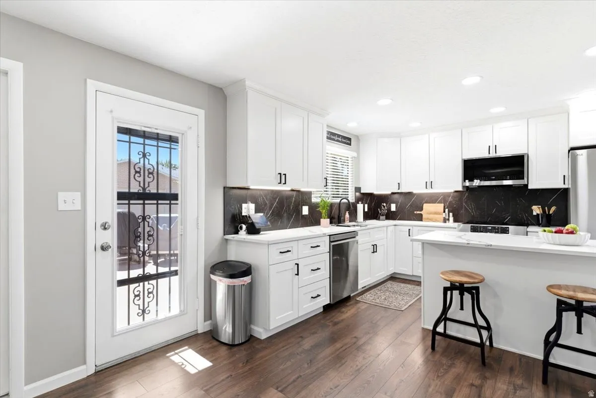 Modern kitchen with white cabinetry and dark wood-finish flooring