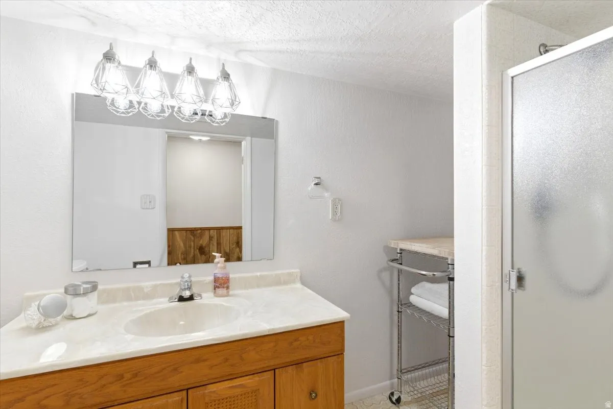 Bathroom vanity featuring a single basin sink, laminate countertop, and wood-finish cabinetry