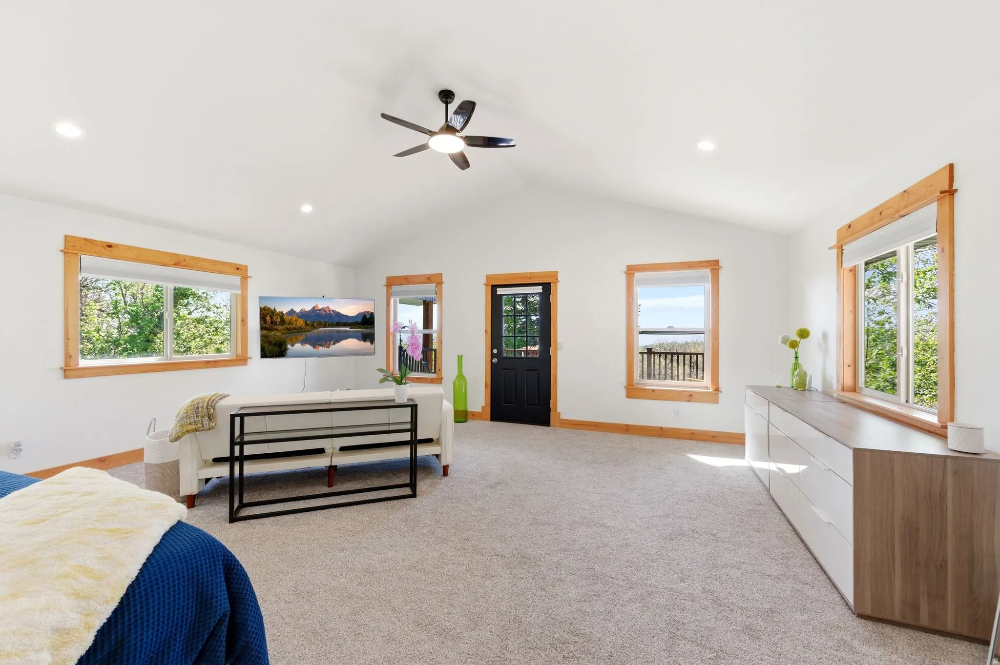Spacious interior room featuring a vaulted ceiling with a ceiling fan