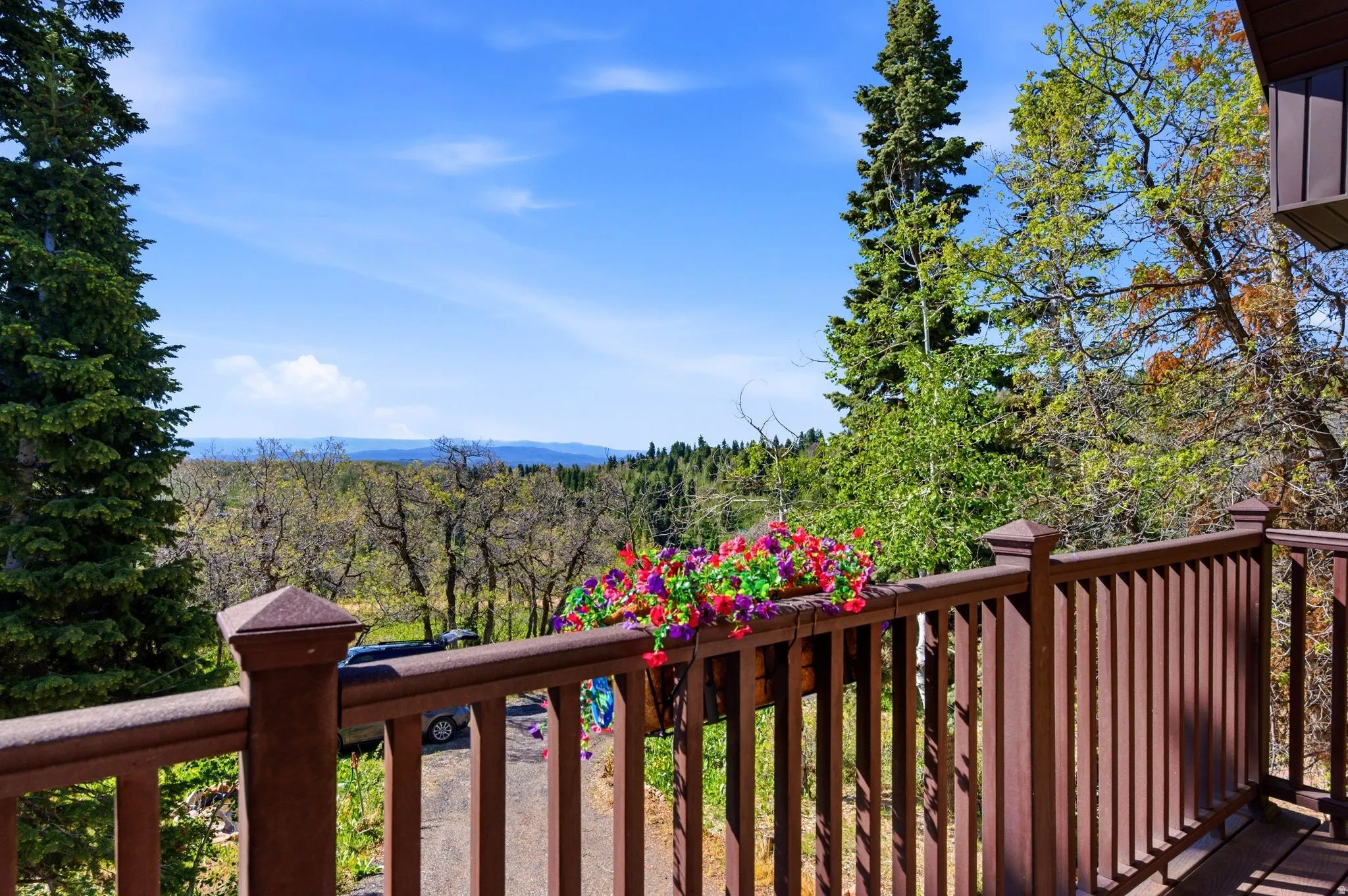 Exterior balcony featuring a brown wood-finish railing with a decorative planter