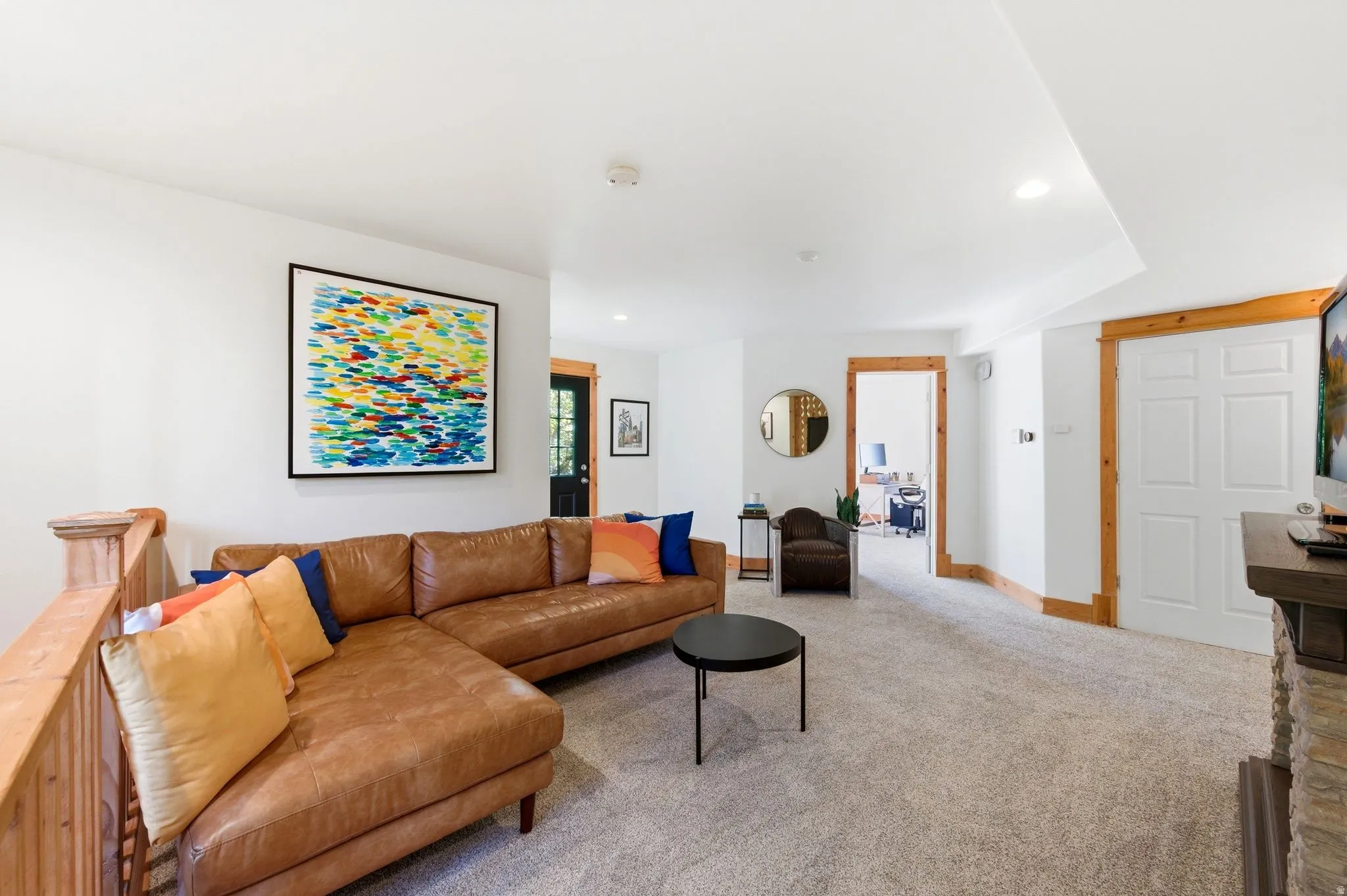 Spacious living area featuring light-toned carpeting, white walls, and natural wood trim