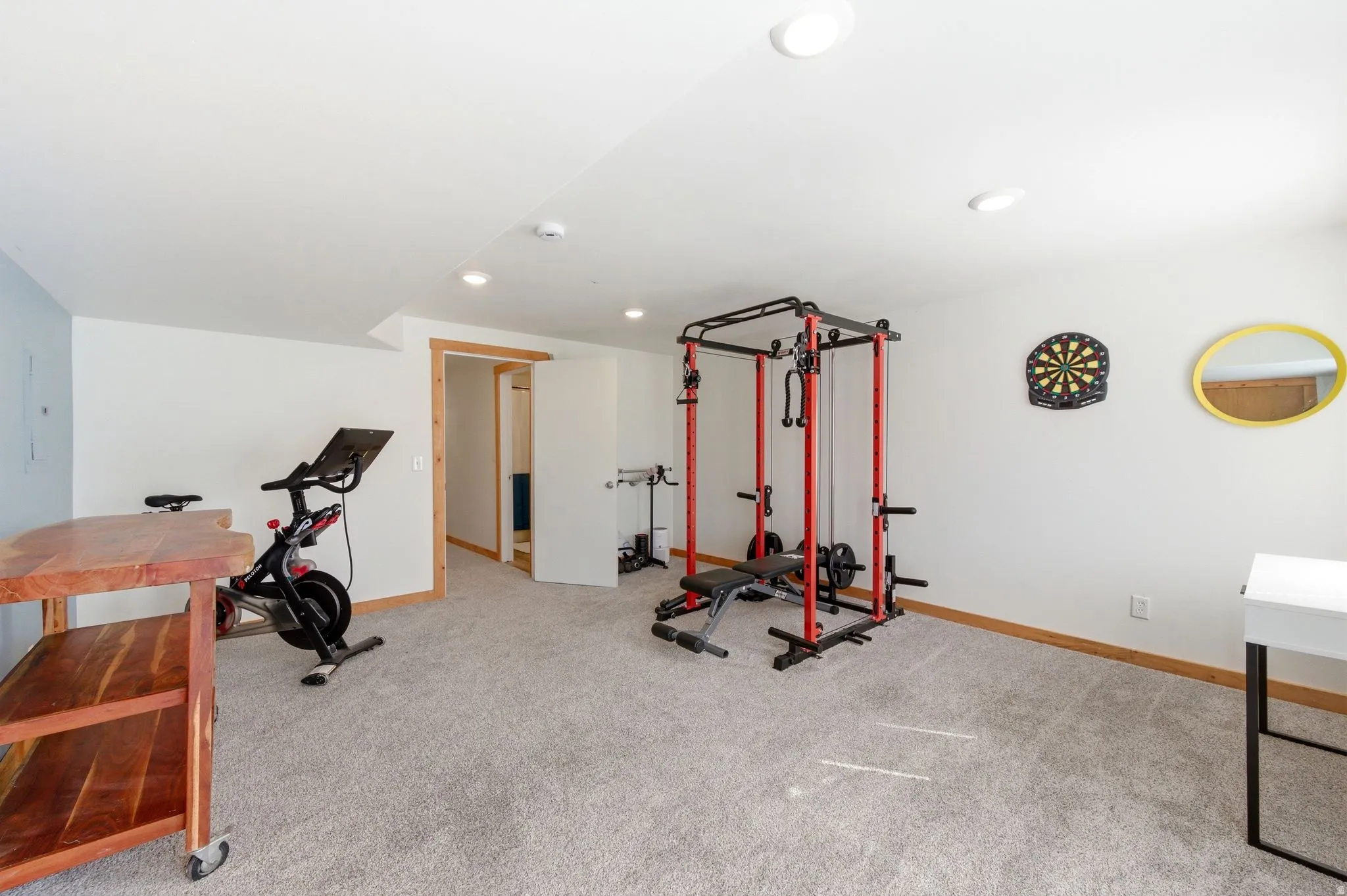 Spacious room featuring light gray carpeting, recessed ceiling lighting, and a neutral wall color with a light blue accent wall