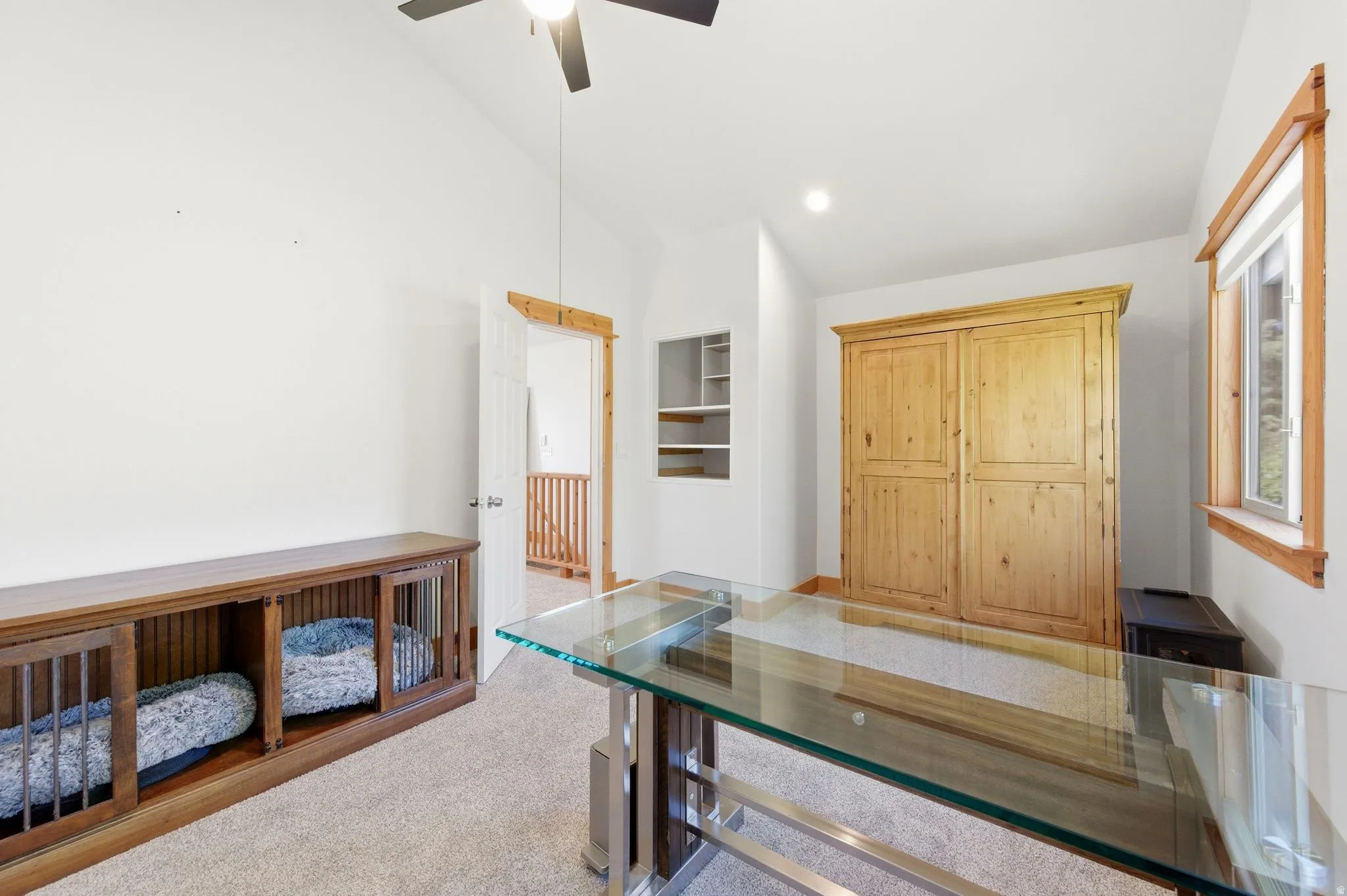 Vaulted ceiling room featuring light tan carpeting and a ceiling fan