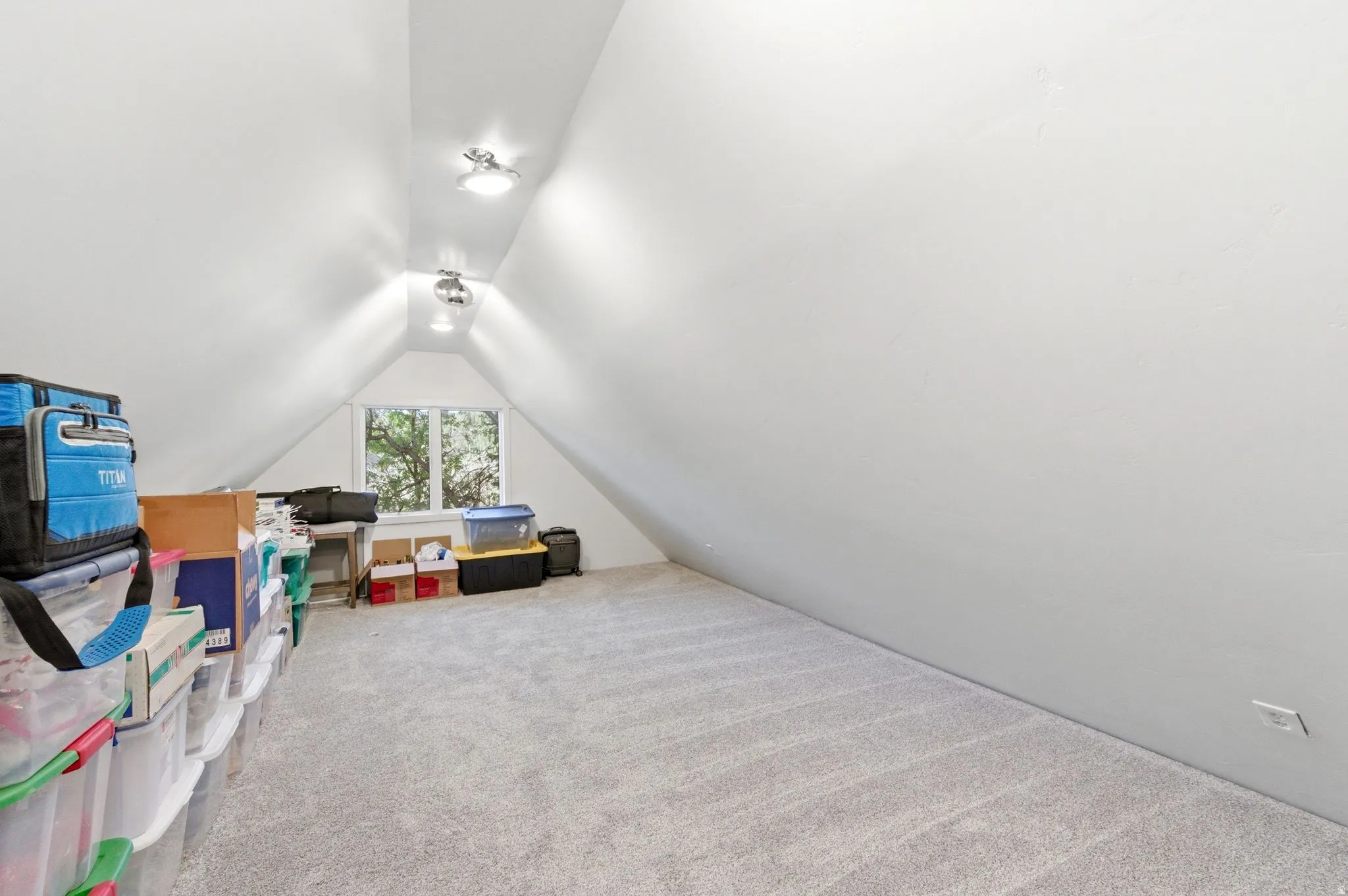 Carpeted attic space with sloped ceilings, recessed lighting, and a single window