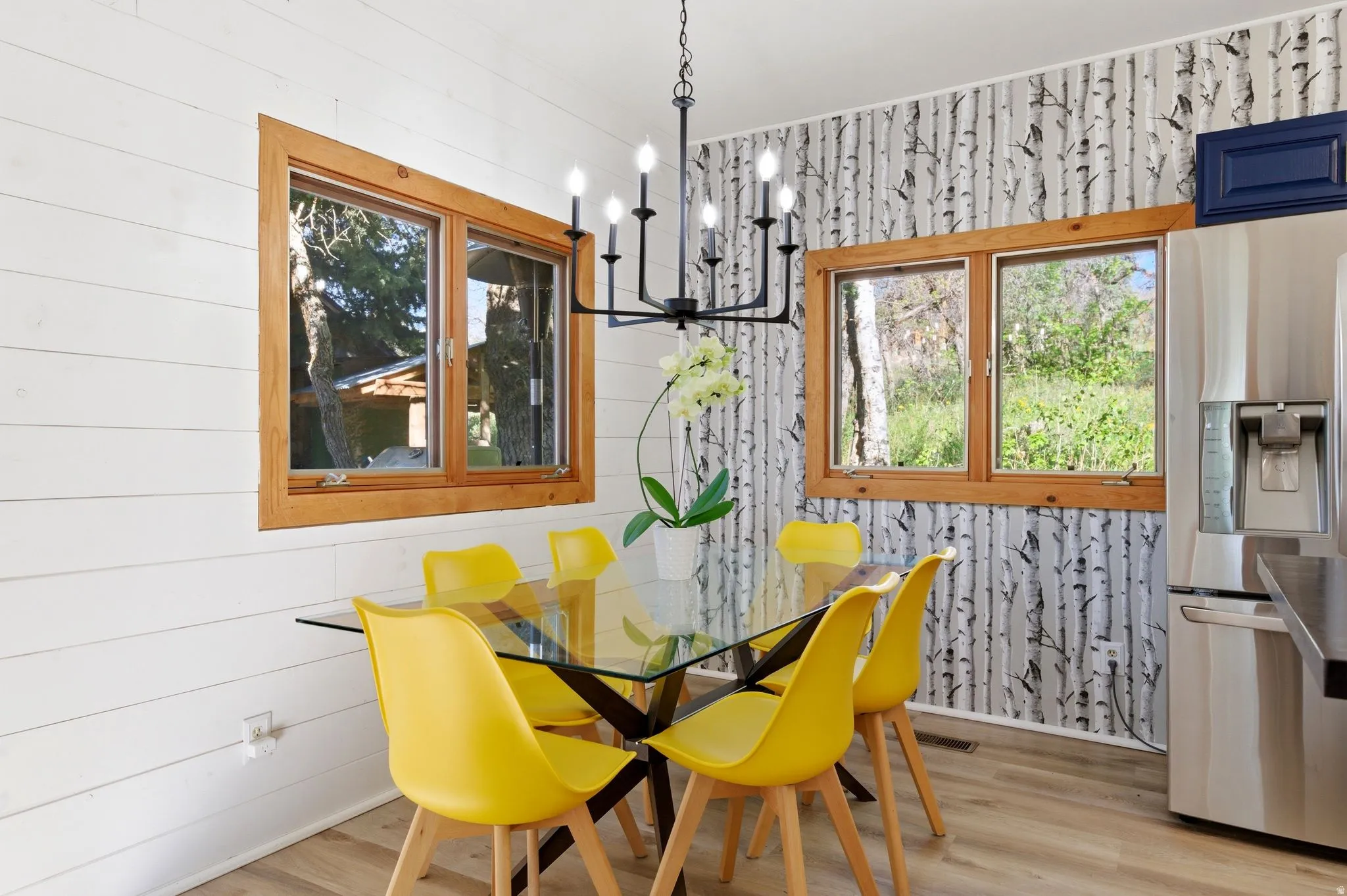 Dining area featuring wood-finish flooring, white shiplap wall, and a patterned accent wall