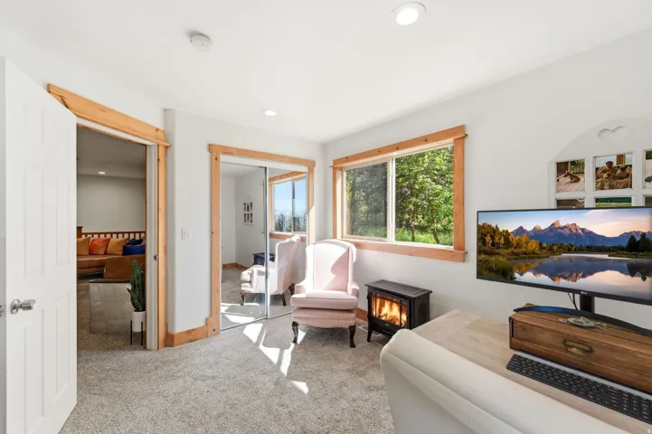 Carpeted interior space featuring white walls and natural wood trim accents
