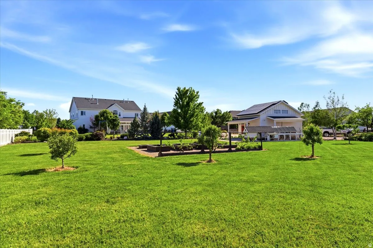 Expansive grassy area featuring multiple young trees and a raised garden bed
