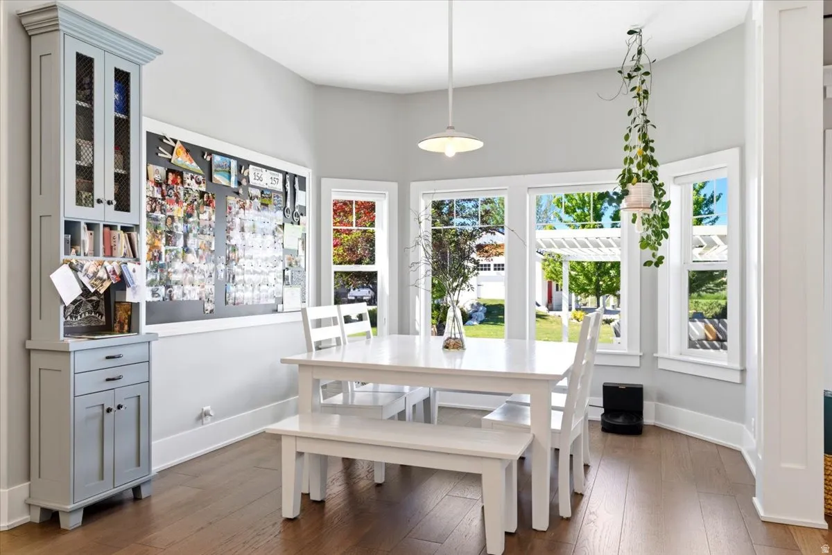 Bright dining area featuring wood-finish flooring and a built-in light blue hutch with mesh cabinet doors