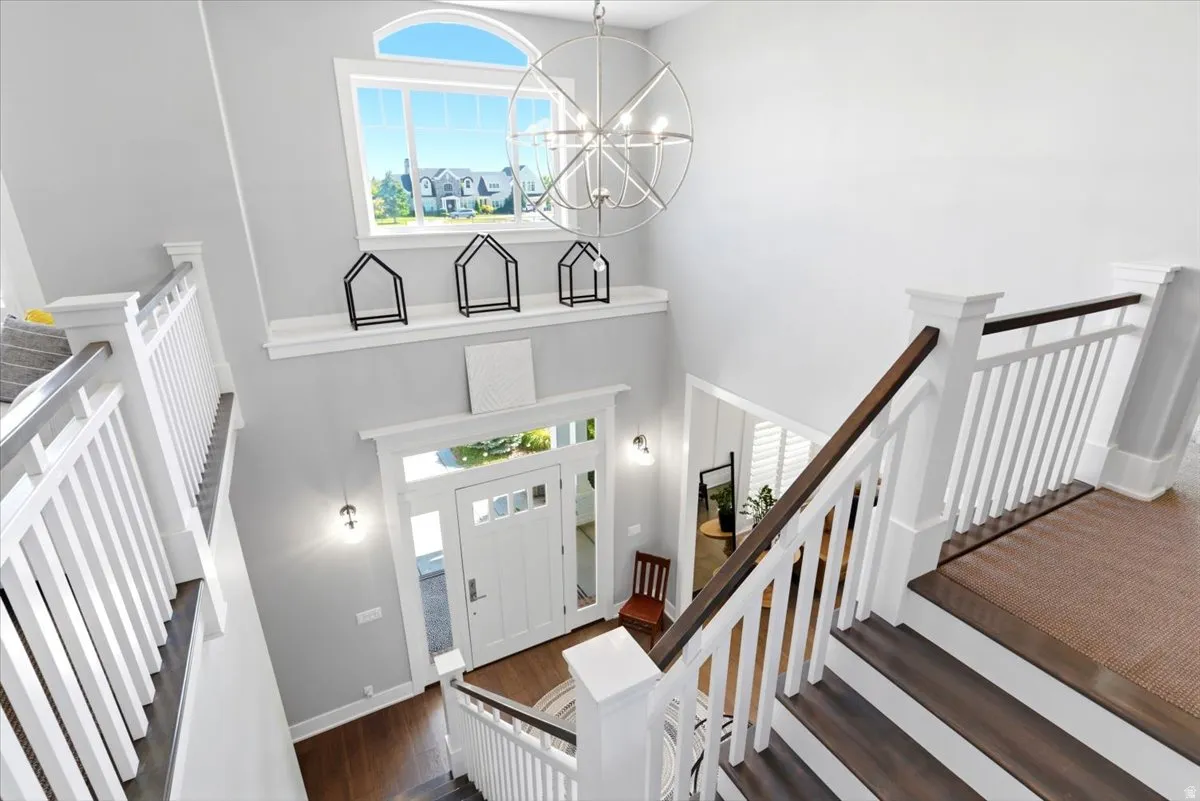 Two-story foyer featuring a prominent arched window, a contemporary spherical chandelier, and a bright white paneled front door with sidelights