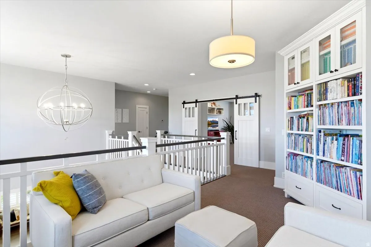 Open loft area featuring a contemporary drum pendant light, white baluster railings with black handrails, and built-in shelving with glass-front upper cabinets