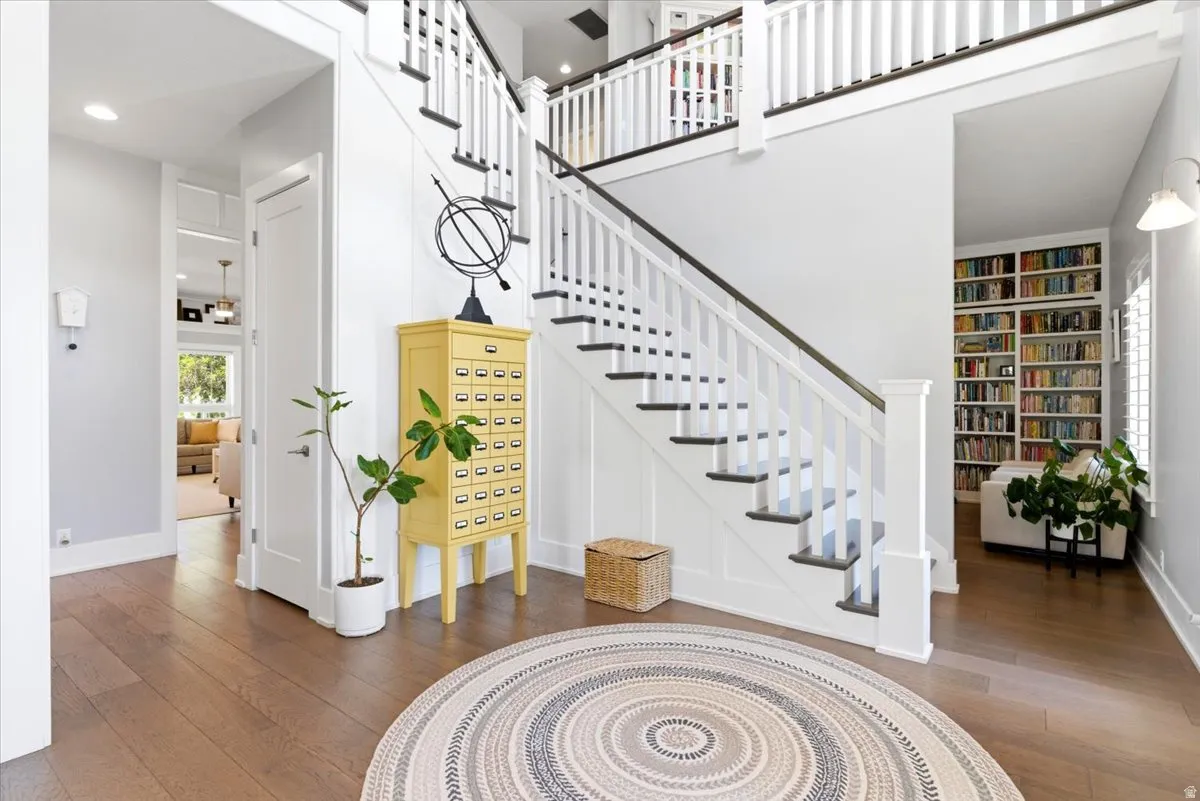 Grand entry foyer featuring wood-finish flooring and a multi-level staircase with white balusters and dark treads