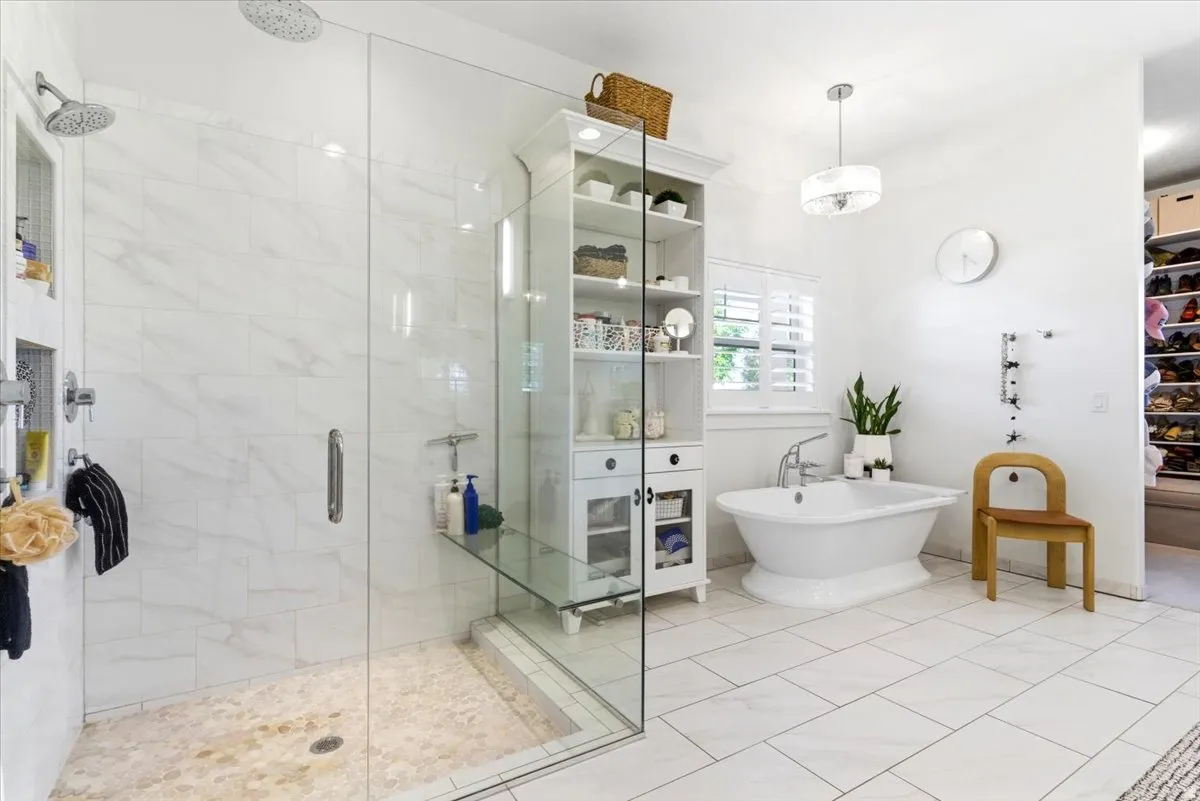 Glass-enclosed shower with dual showerheads and pebble-tile floor