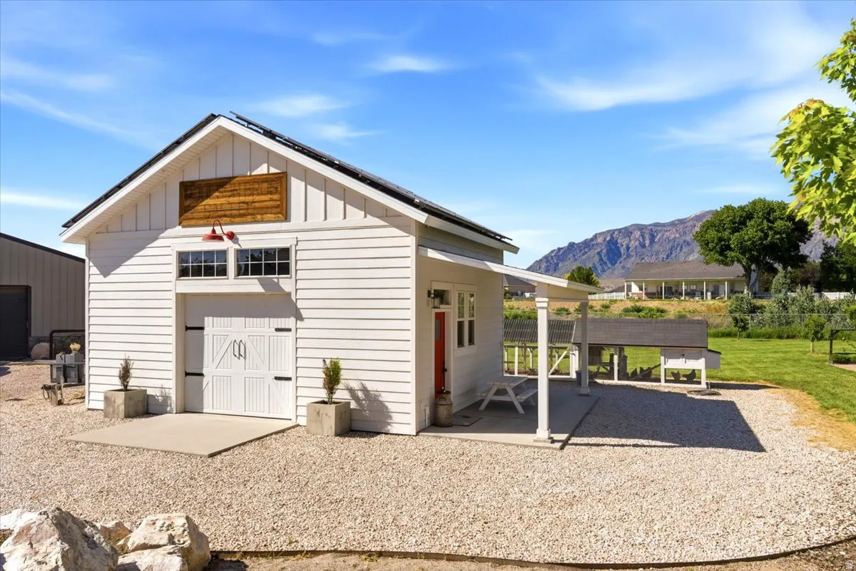White siding outbuilding with a gabled roof and carriage-style doors