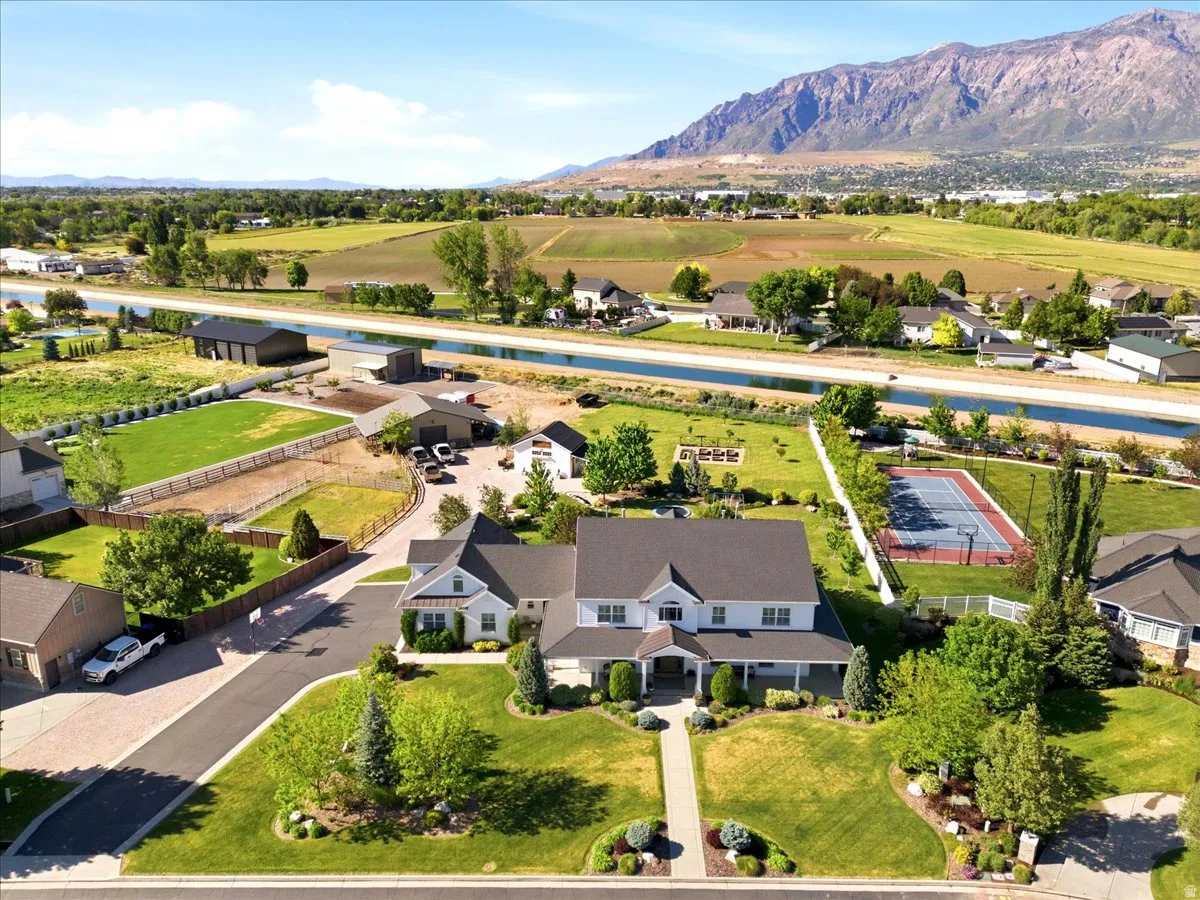 Expansive property featuring a large residence with a front porch, a separate, mature landscaping, and mountain scenery