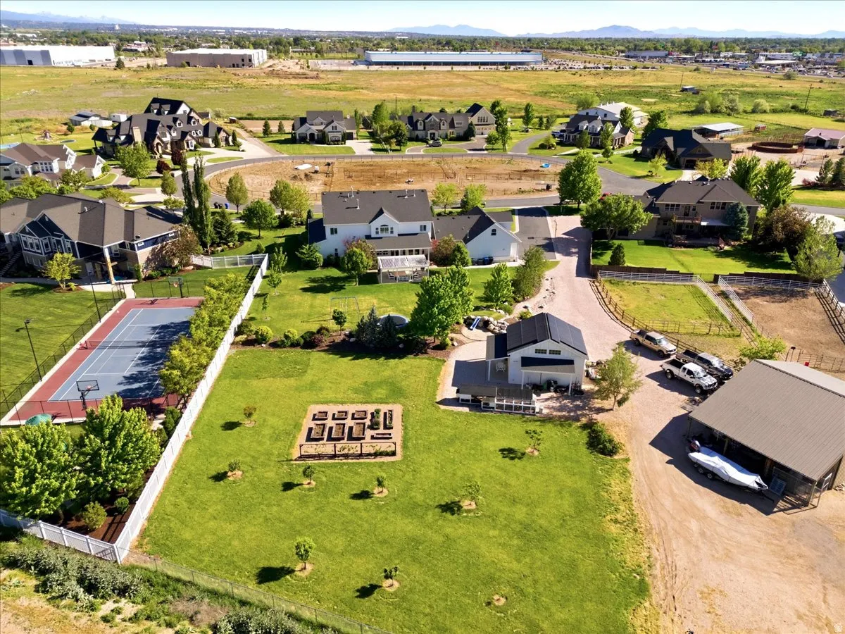 Expansive property featuring a private tennis/basketball court, raised garden beds, a contemporary barn-style outbuilding, and ample open green space