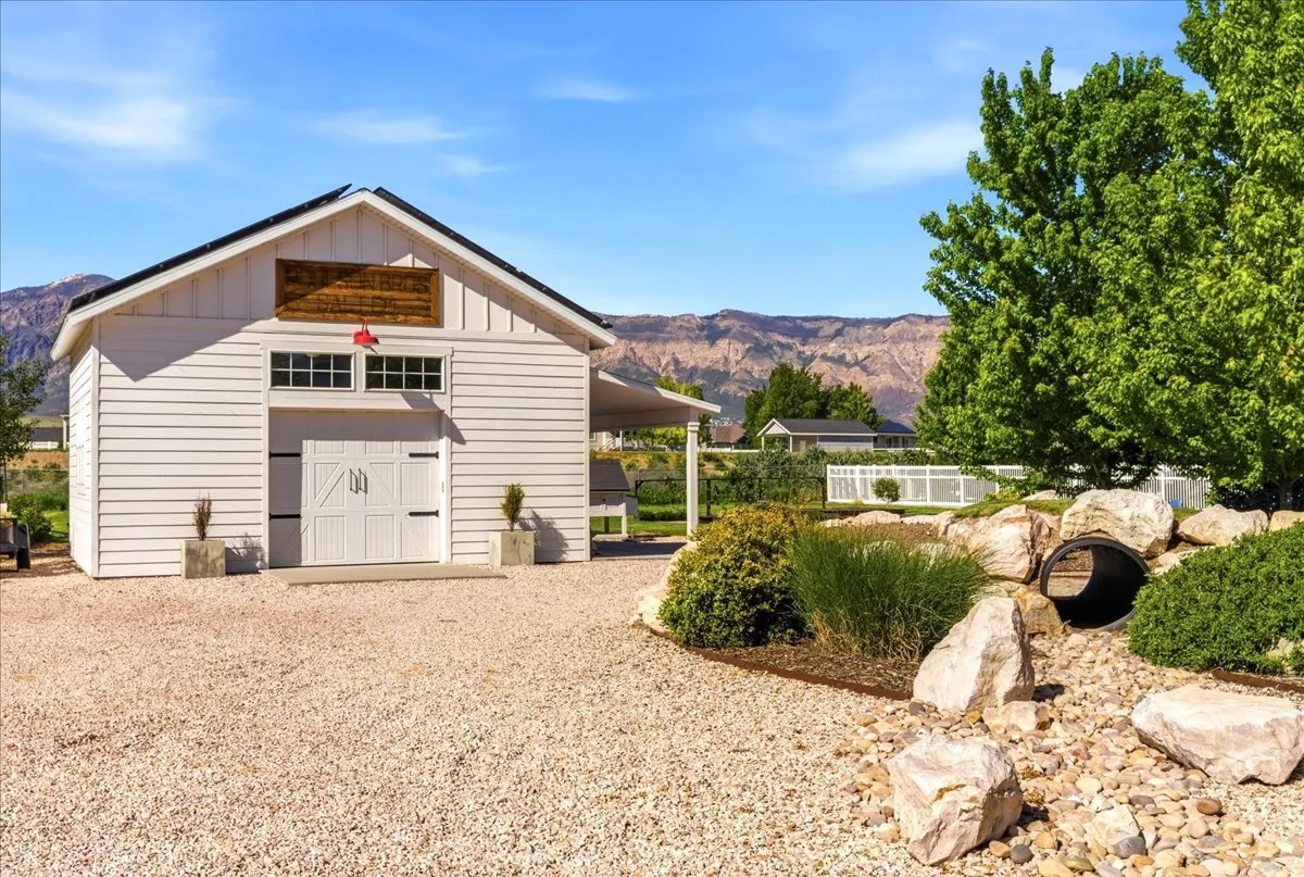 White siding accessory dwelling unit with double carriage doors and an overhead wood-finish sign
