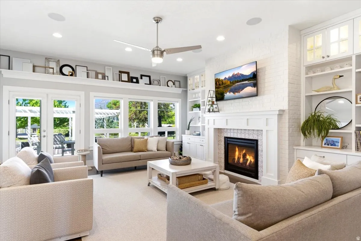 Spacious living area featuring a central fireplace with decorative tile surround and white mantel, built-in shelving, abundant natural light from multiple windows, and recessed lighting
