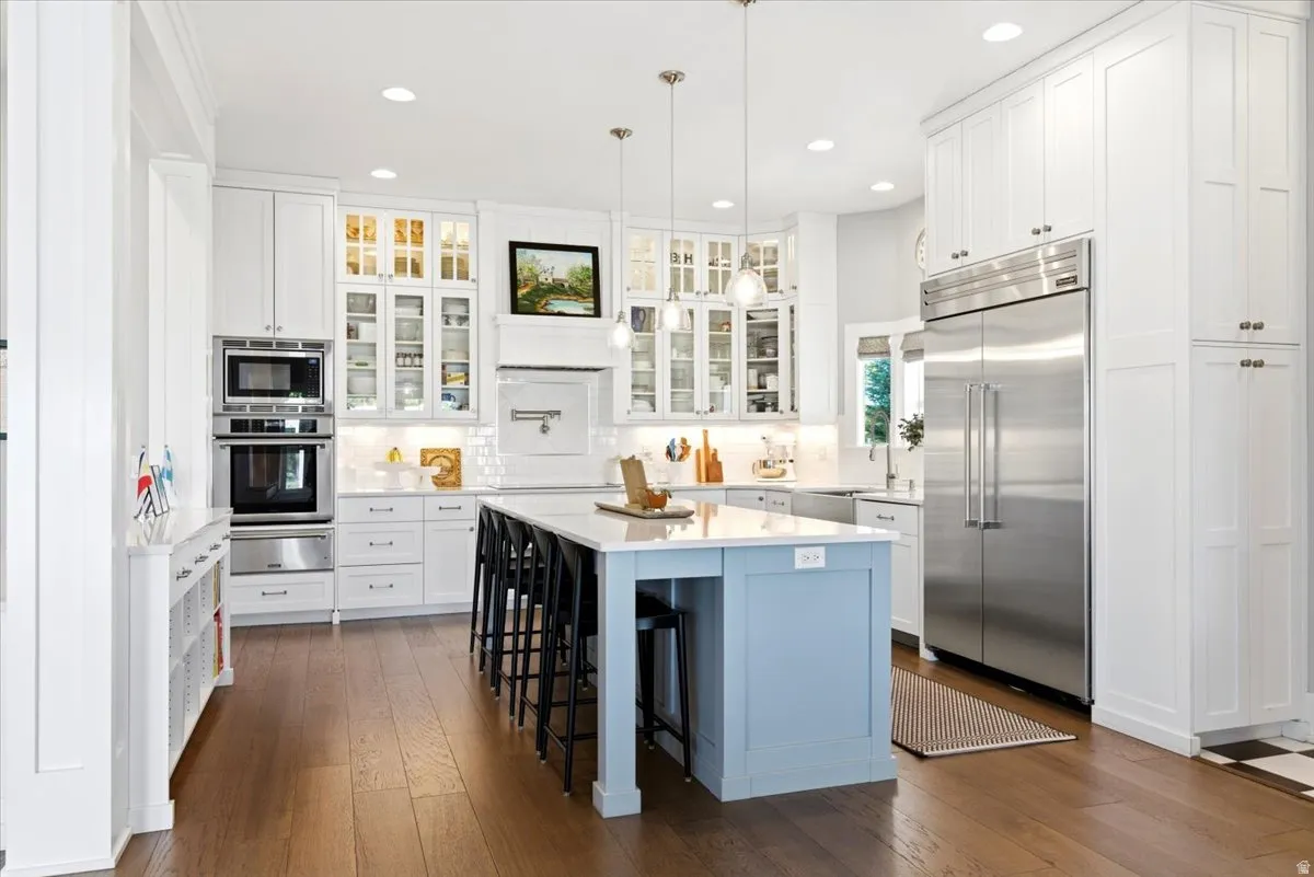 Spacious kitchen featuring wood-finish flooring and extensive white cabinetry