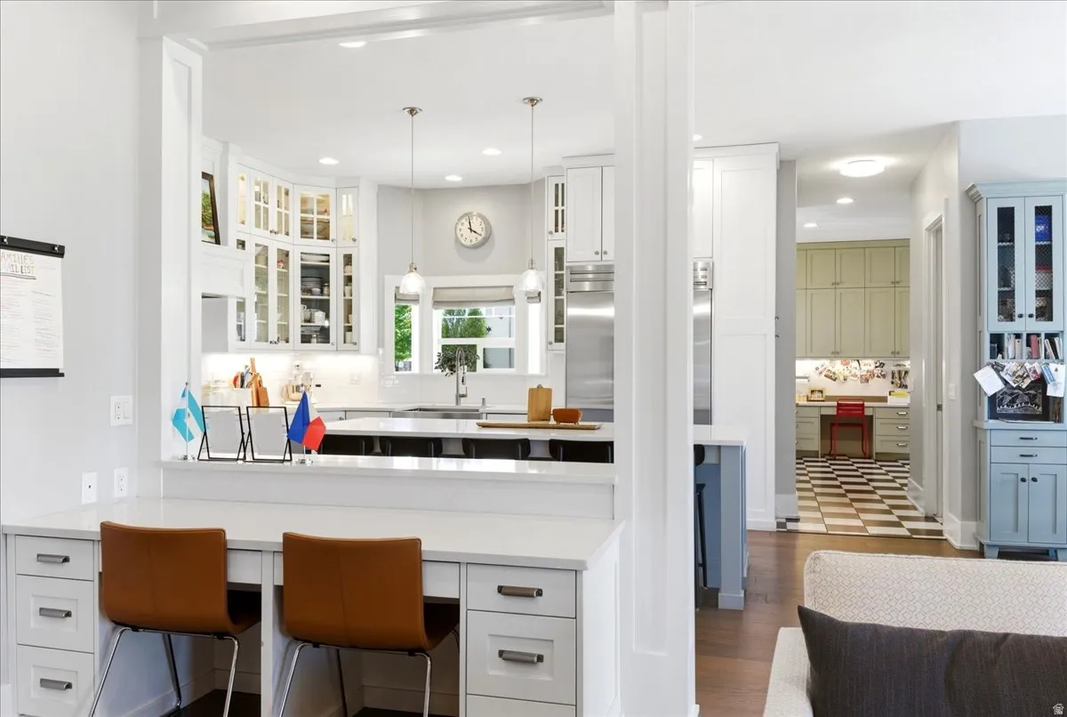 Open-concept design featuring a kitchen with white cabinetry, stainless steel appliances, and a central island