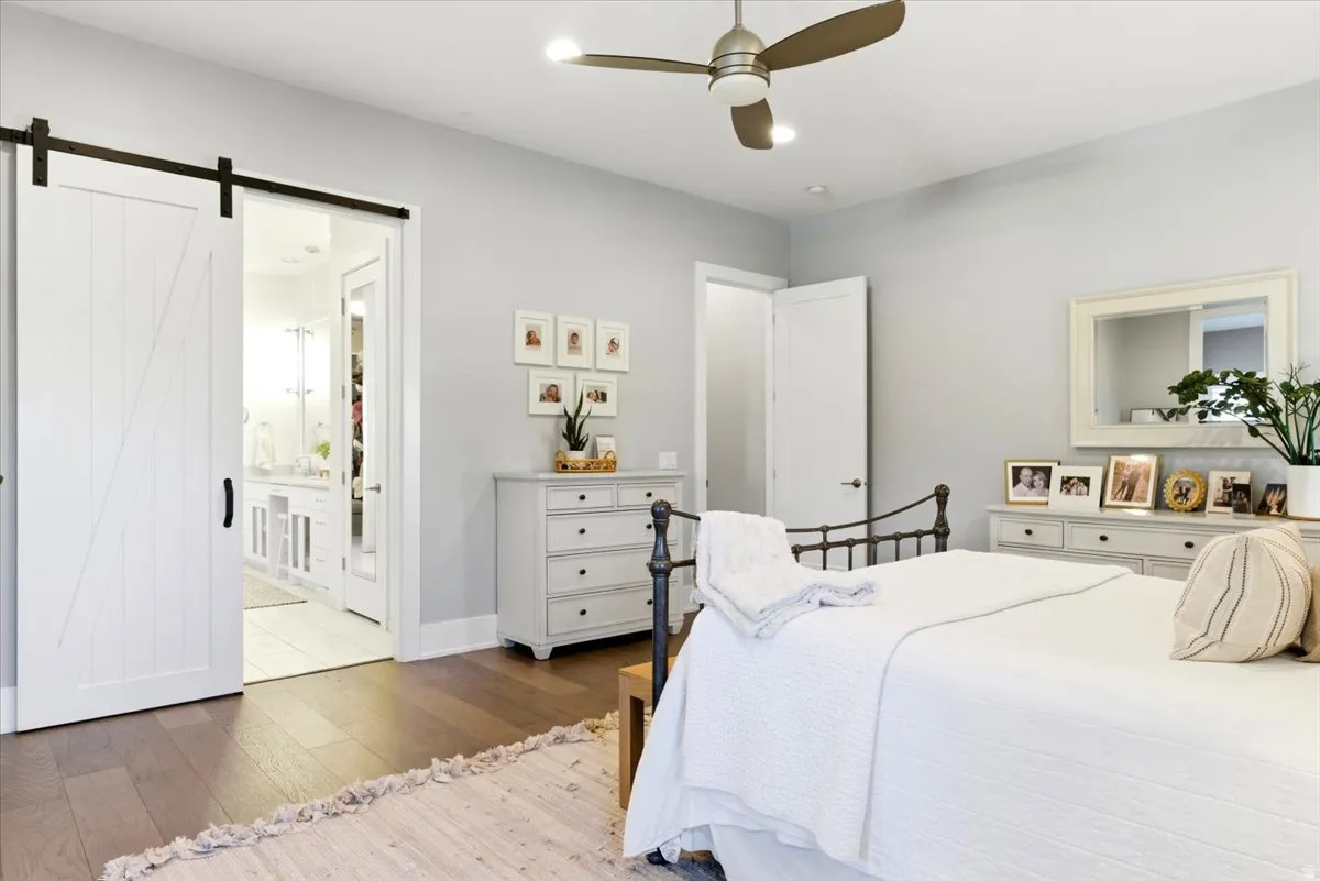 Spacious room featuring wood-finish flooring, a contemporary ceiling fan with integrated lighting, and light gray wall paint